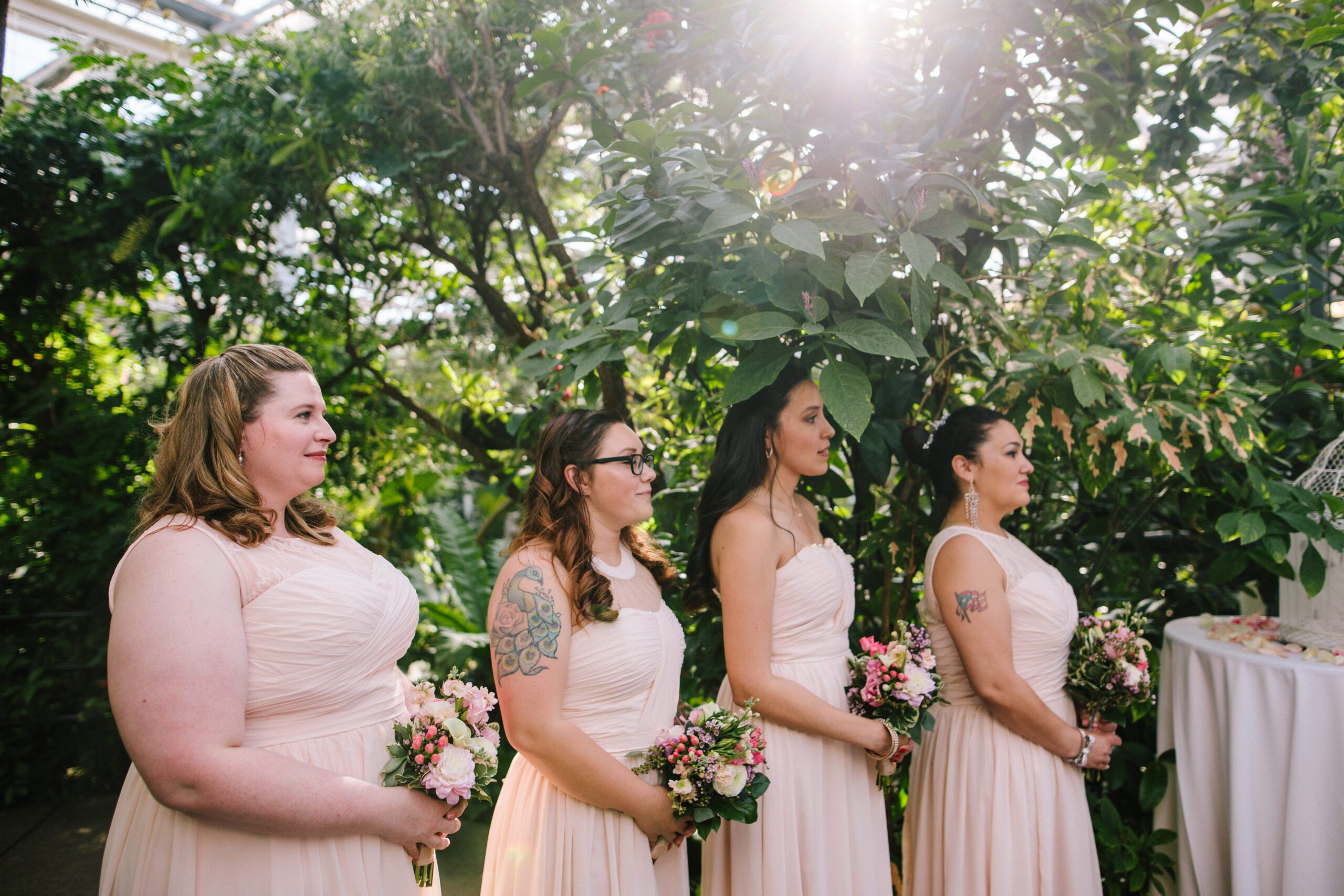 The bridesmaids dressed in beautiful pink gowns listening during the ceremony at the Butterfly Pavilion wedding. 