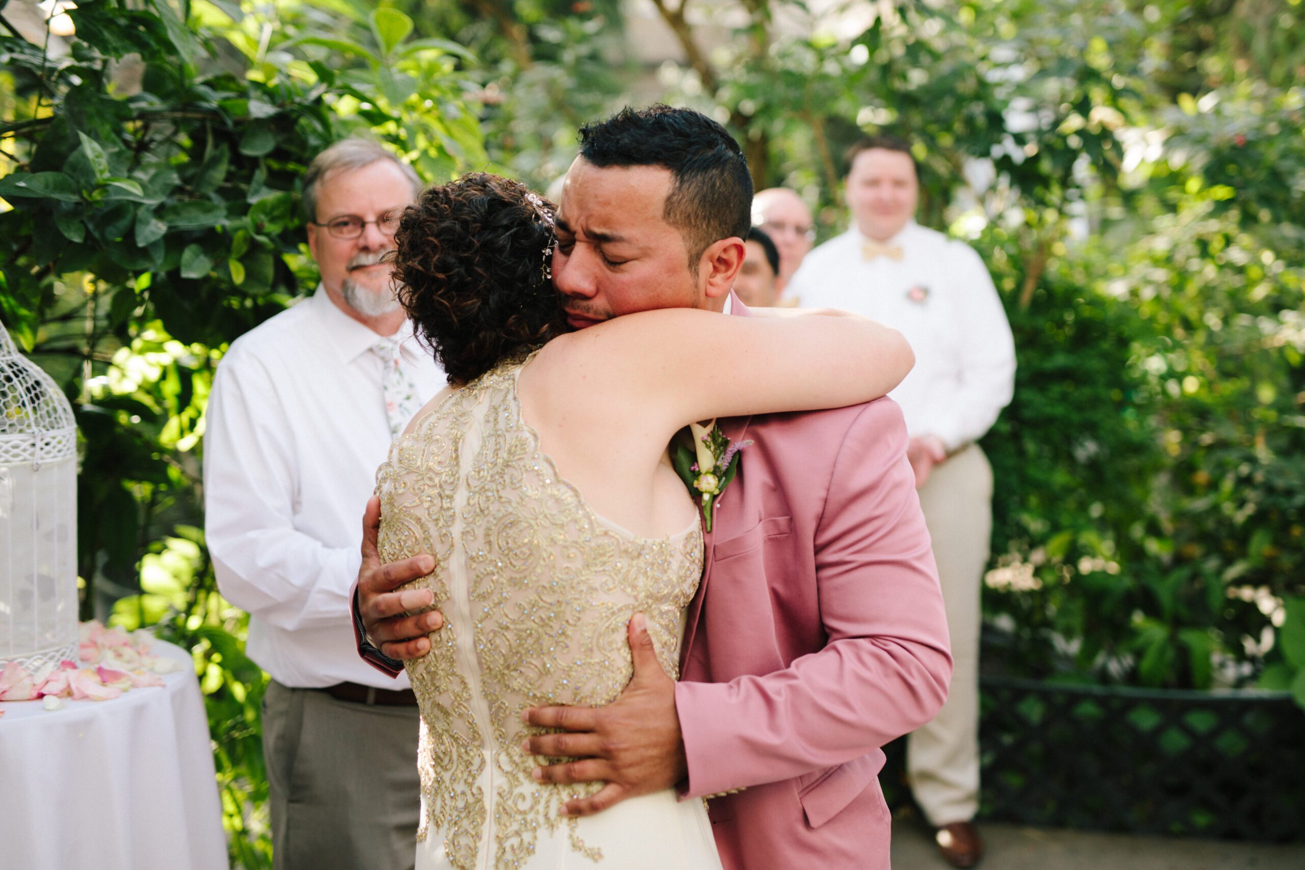 The groom hugs his bride after she shares her emotional vows at their Butterfly Pavilion wedding ceremony. 