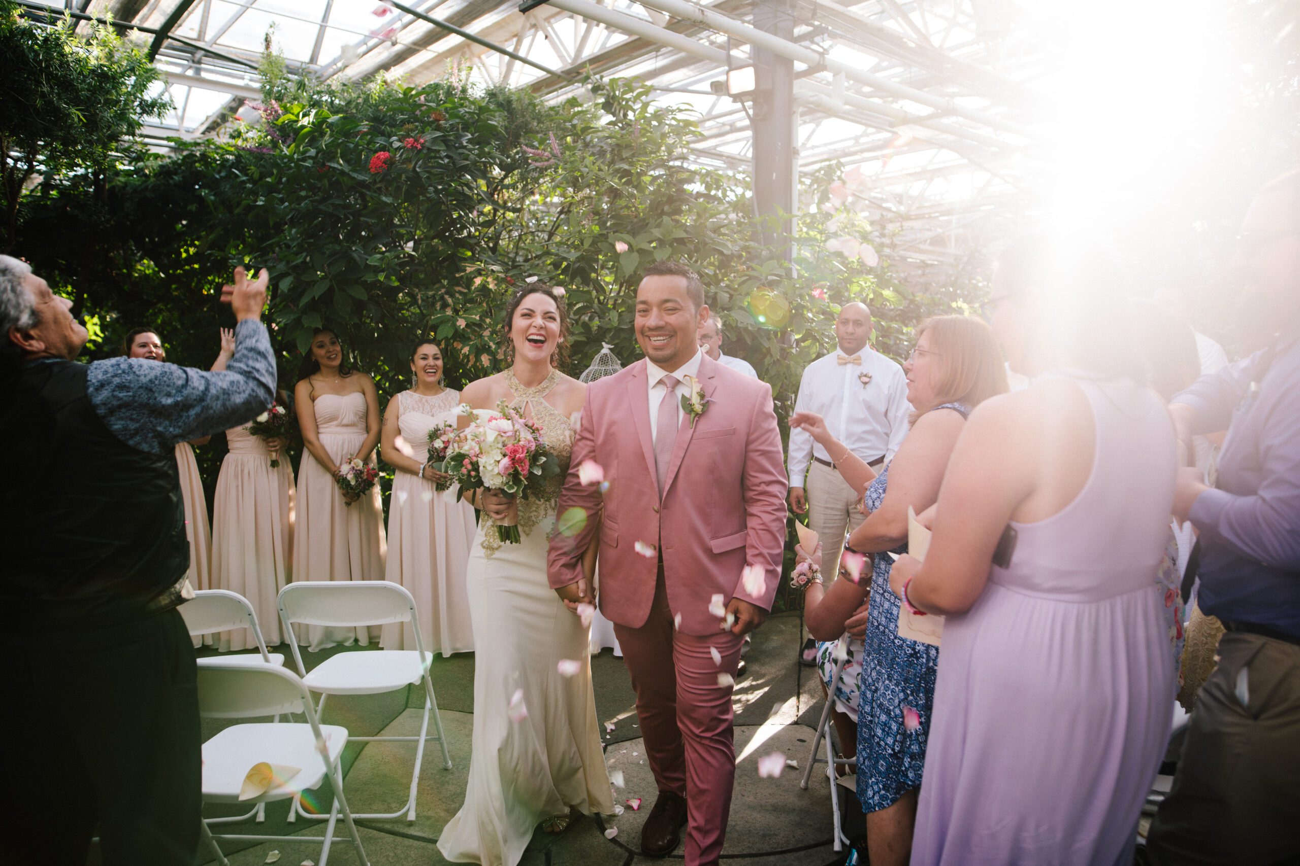 The guests throw flowers in the air as the bride and groom walk down the aisle as husband wife at their Butterfly Pavilion Wedding. 