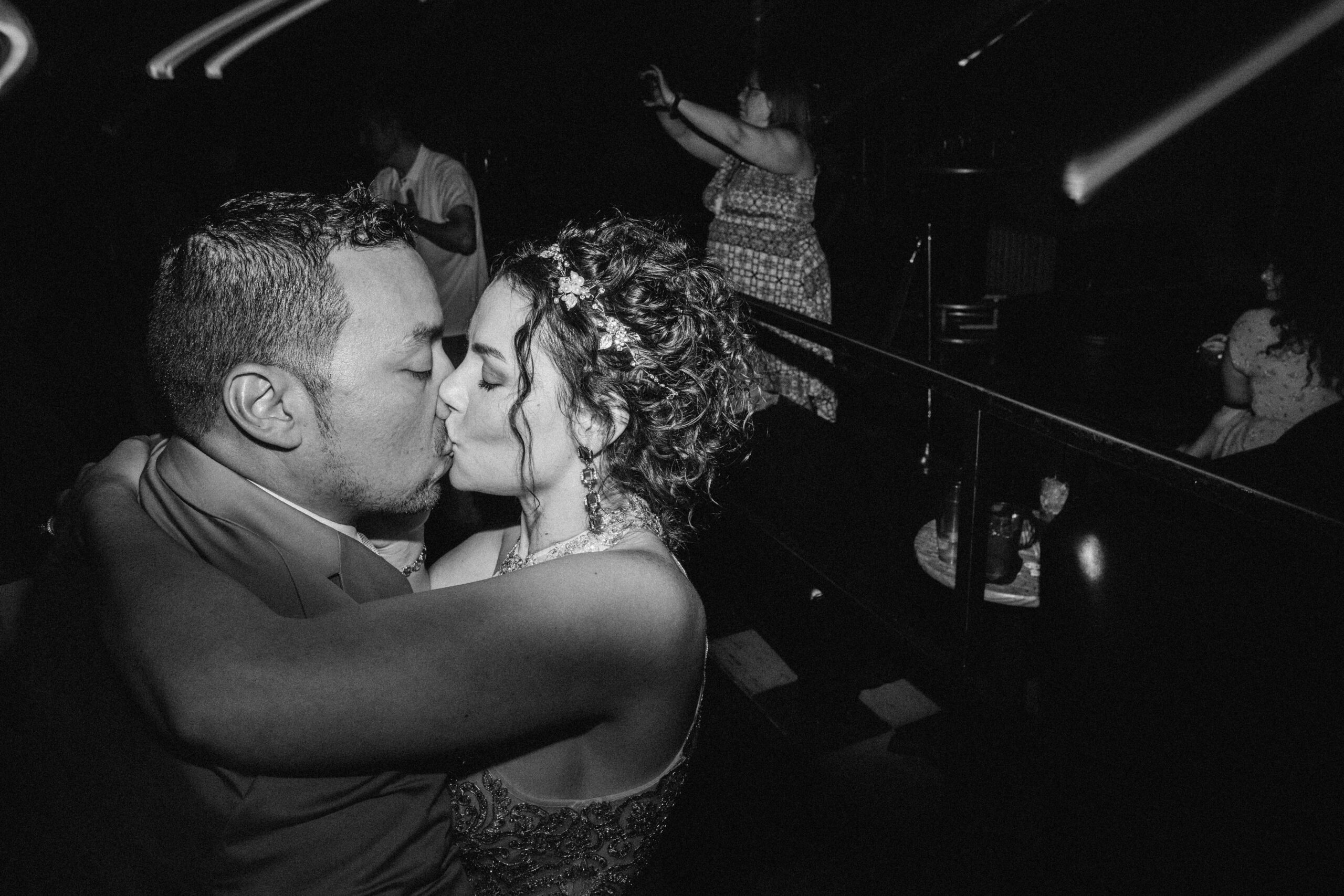 A black and white photo of the bride and groom kissing up close on the dance floor after their wedding at the Butterfly Pavilion. 