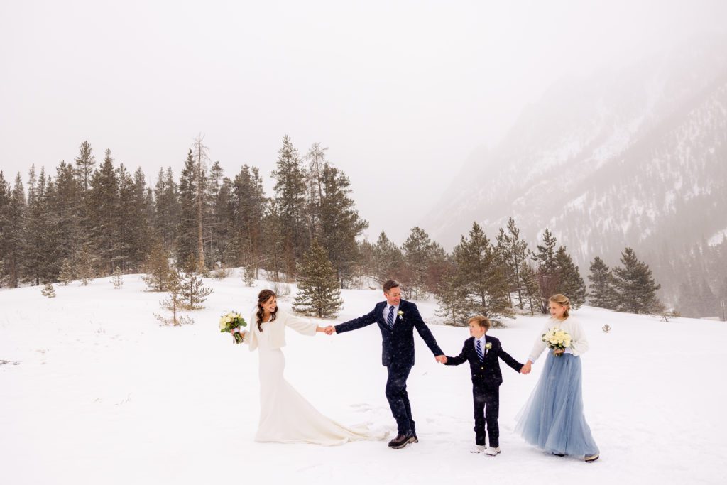 A couple with their kids hikes during their snowy elopement near Copper Mountain 