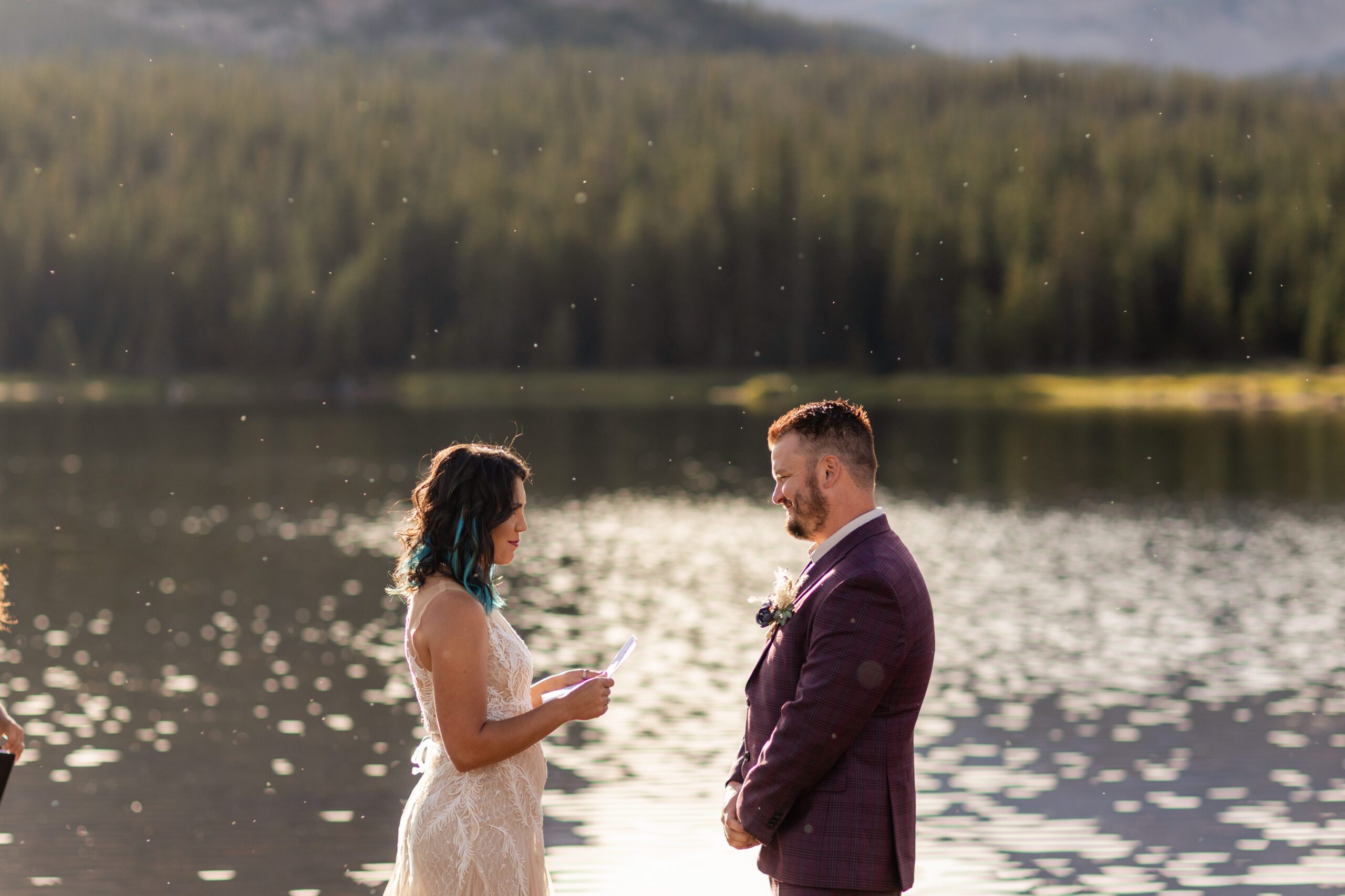 Groom smiling at bride while she reads her vows near the lake during their Brainard Lake Elopement.