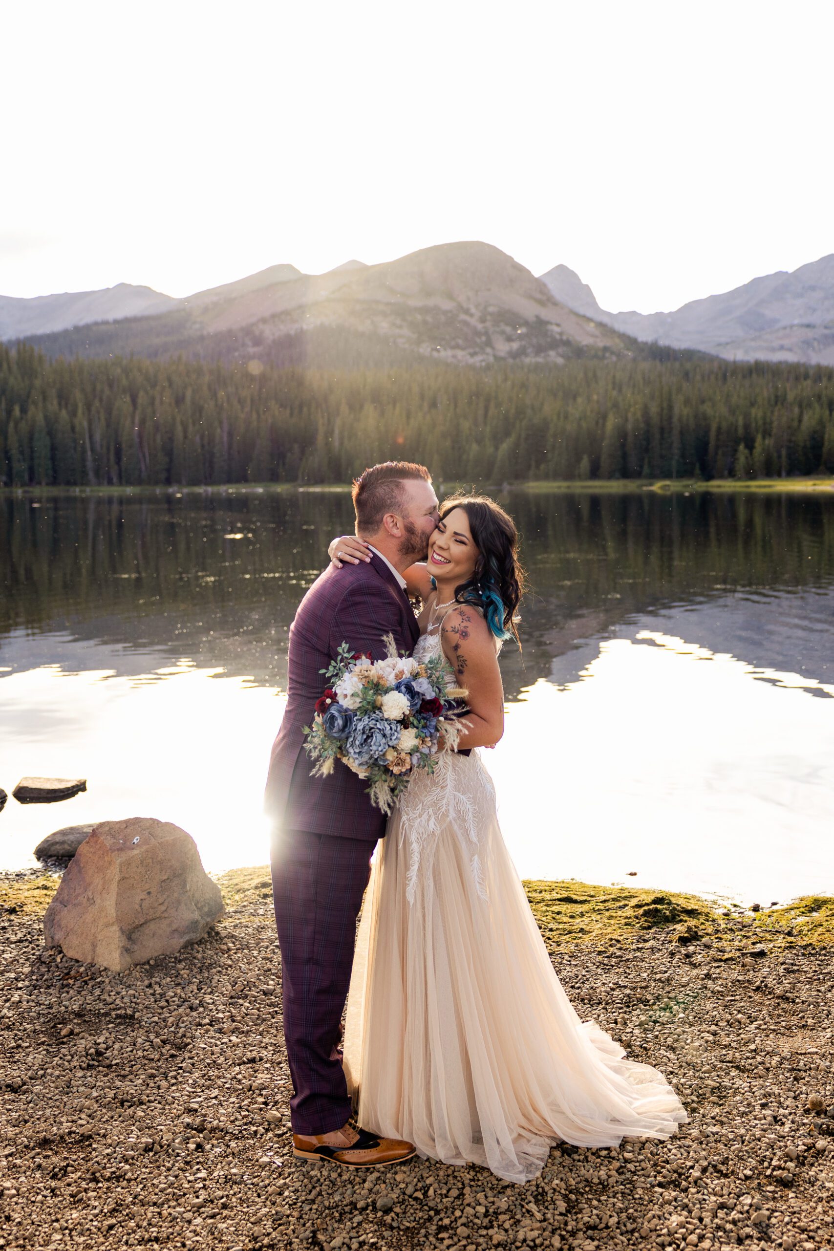 The groom kisses his bride on the cheeks near the lake at their Brainard Lake Elopement.