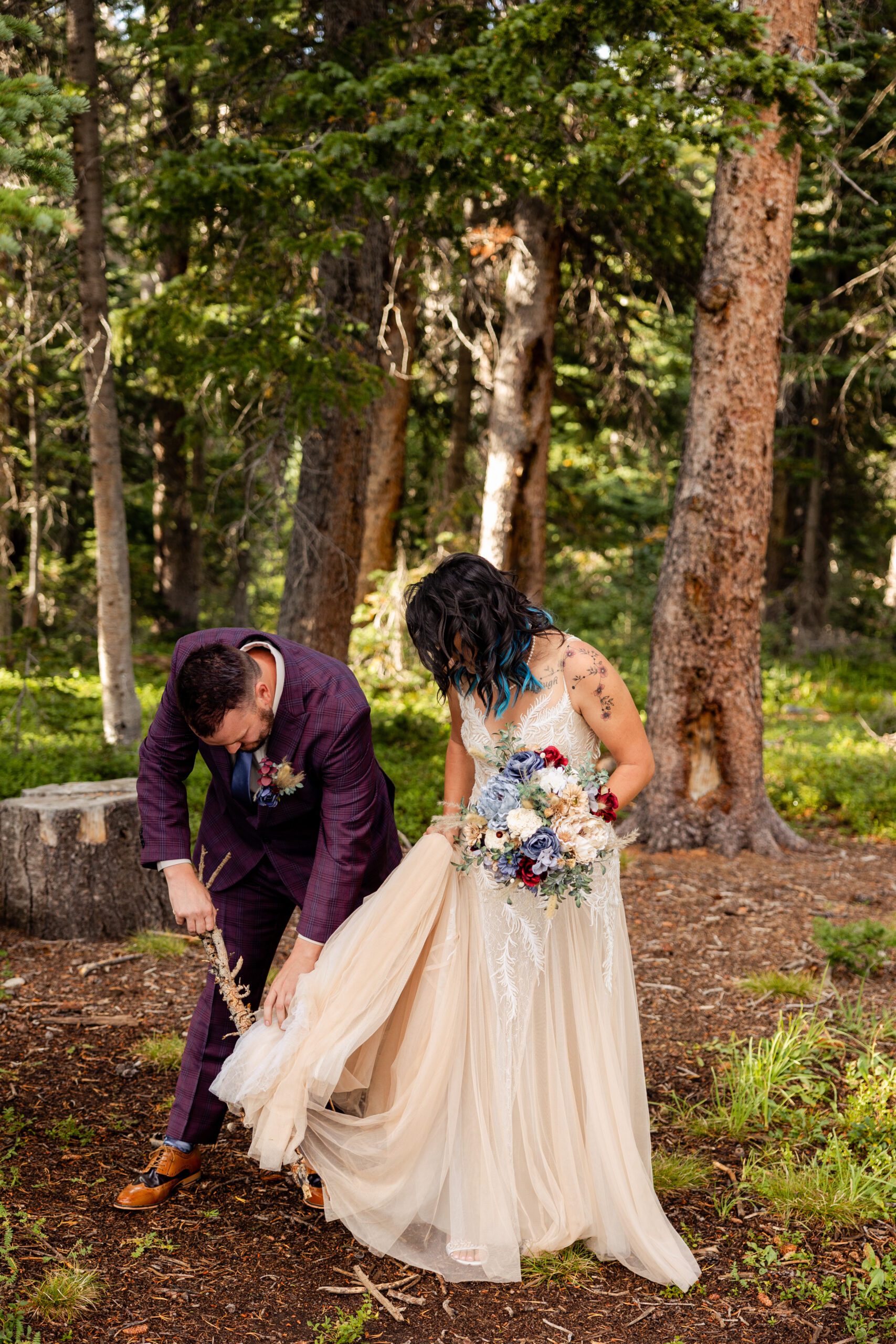 Bride gets caught in a branch, groom helps her detach before their Brainard Lake Elopement. 