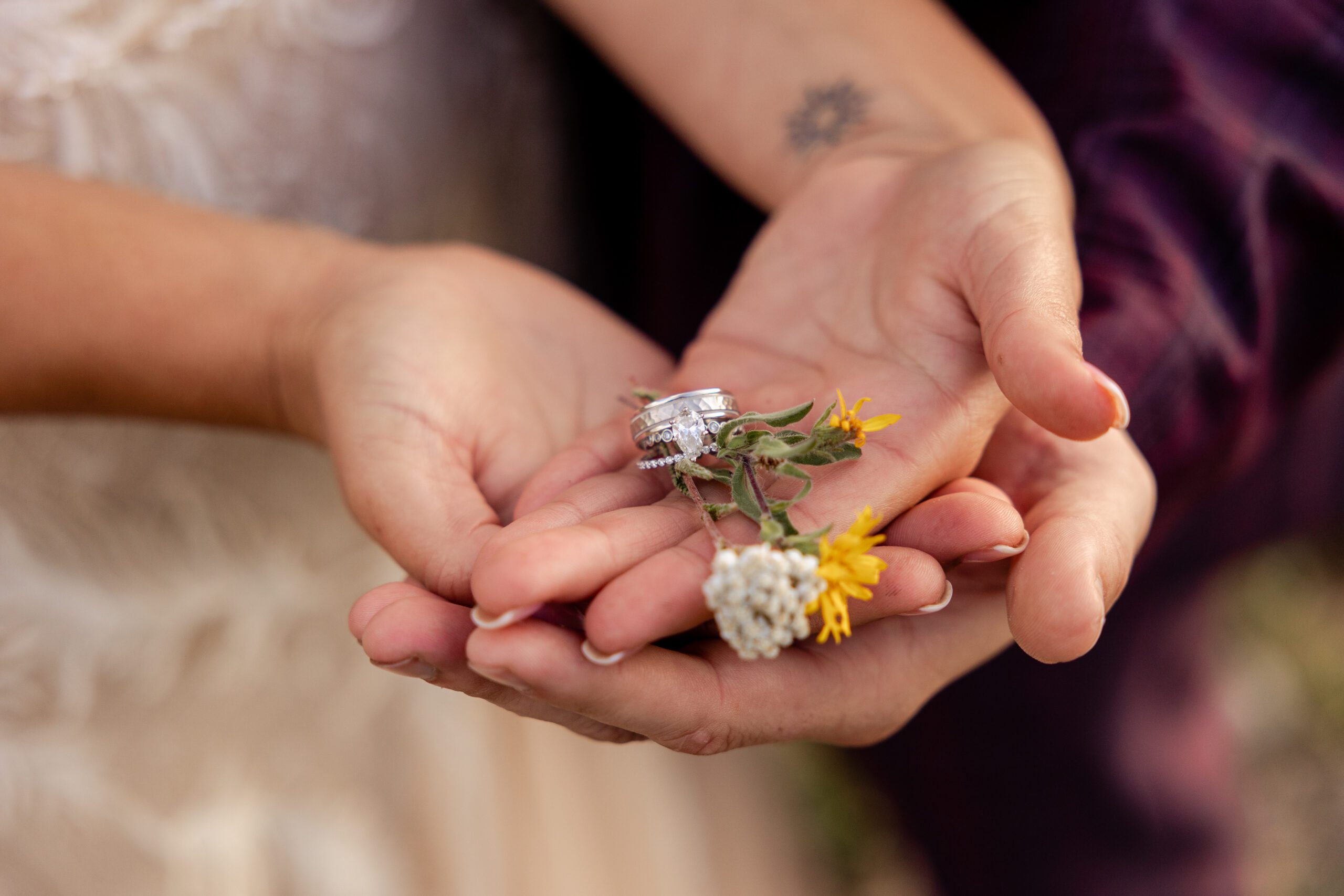 bride and groom hold their rings with wildflowers at their Brainard Lake Elopement.
