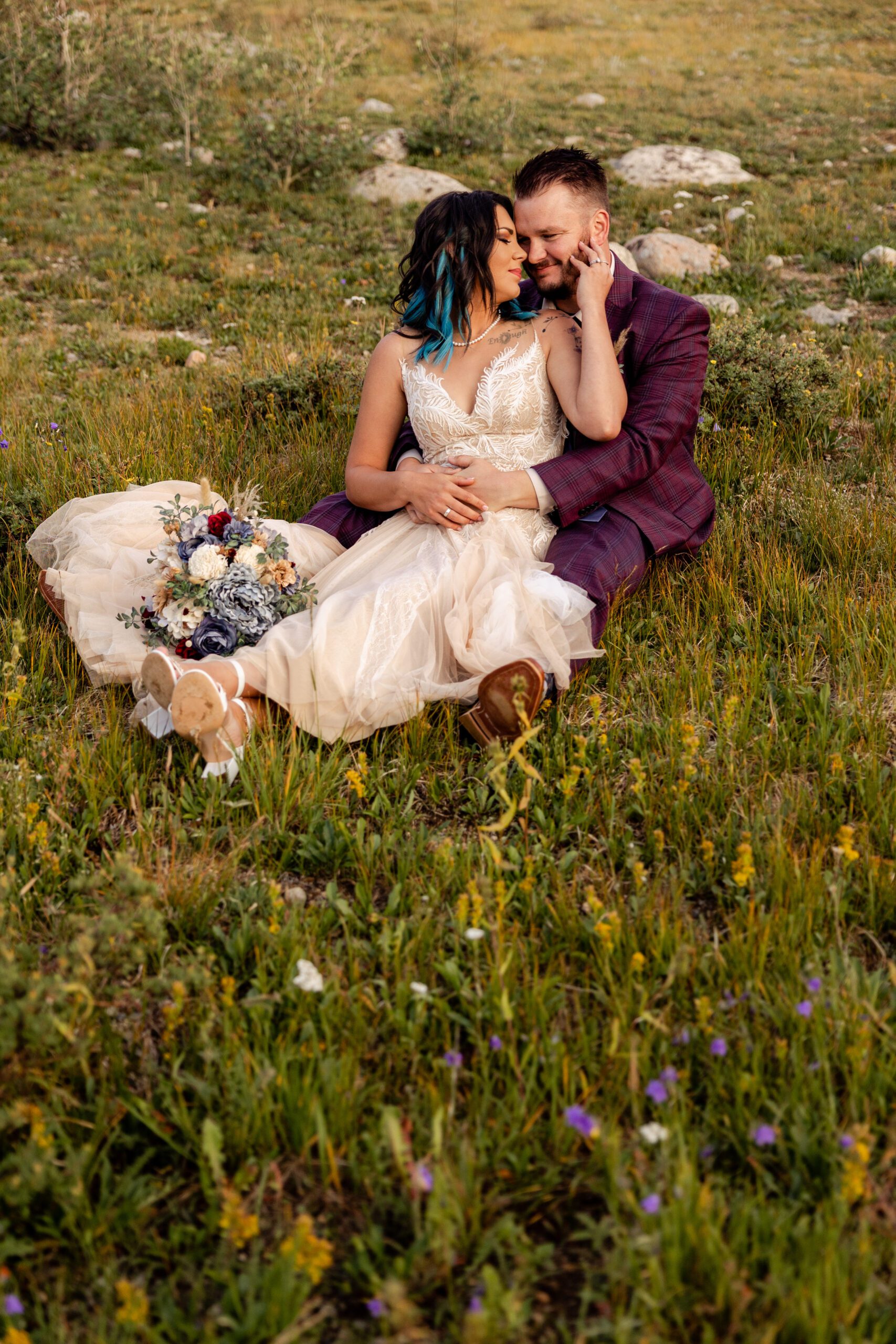 Bride and groom sitting together in a meadow of wildflowers after their Brainard Lake Elopement. 