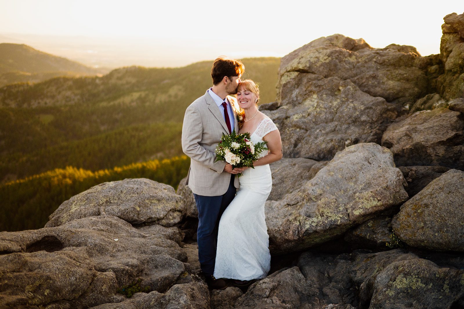 groom kisses his bride's forhead during sunrise at Lost Gulch Overlook