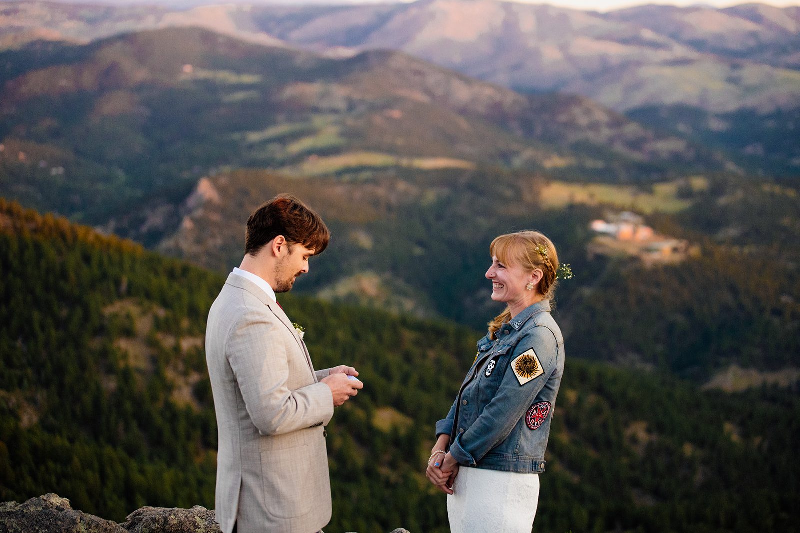 bride smiles sweetly as groom reads his vows at sunrise during Lost Gulch Overlook elopement ceremony