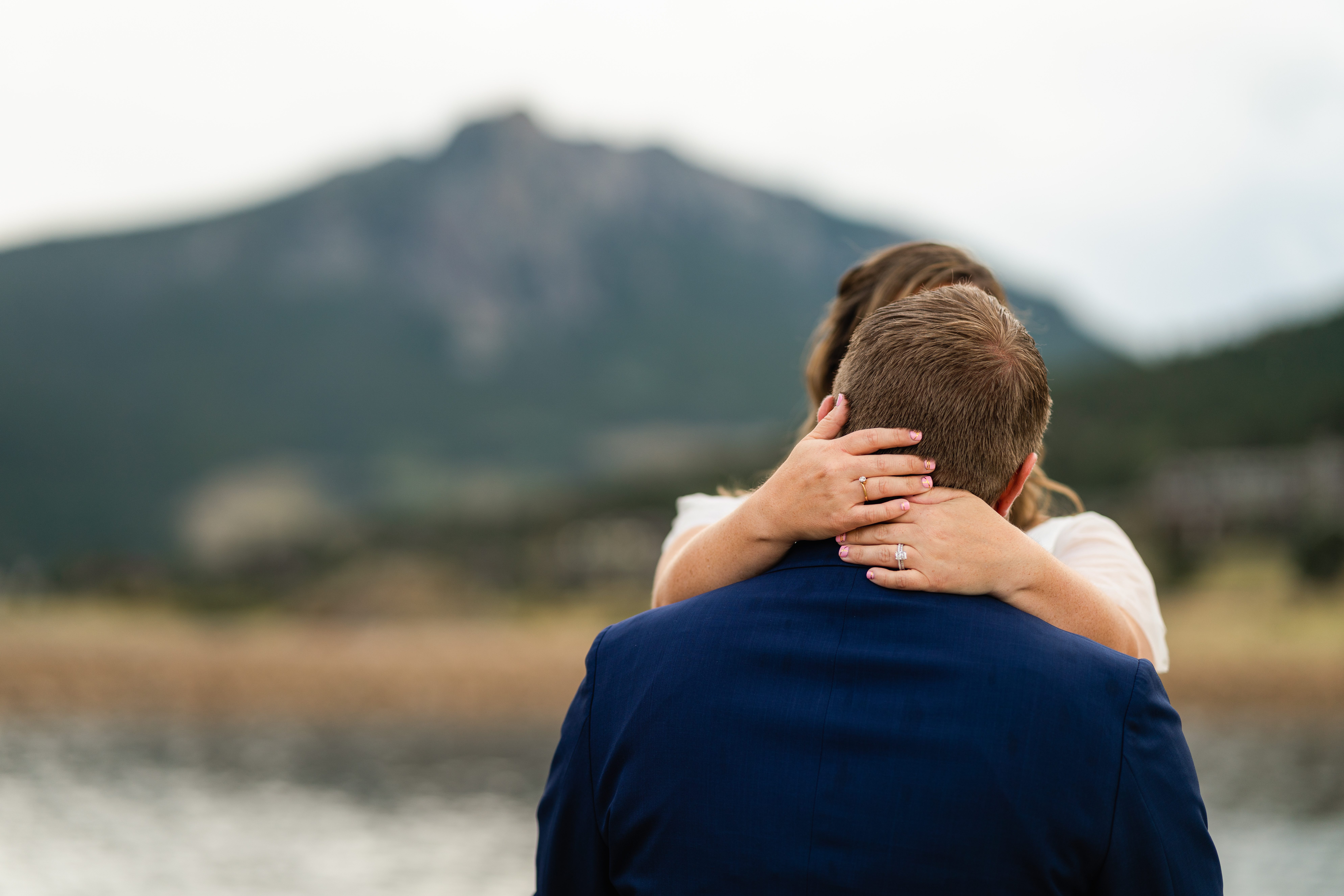 bride wraps her hands around grooms neck - shot of the rings at their Bear Lake elopement. 