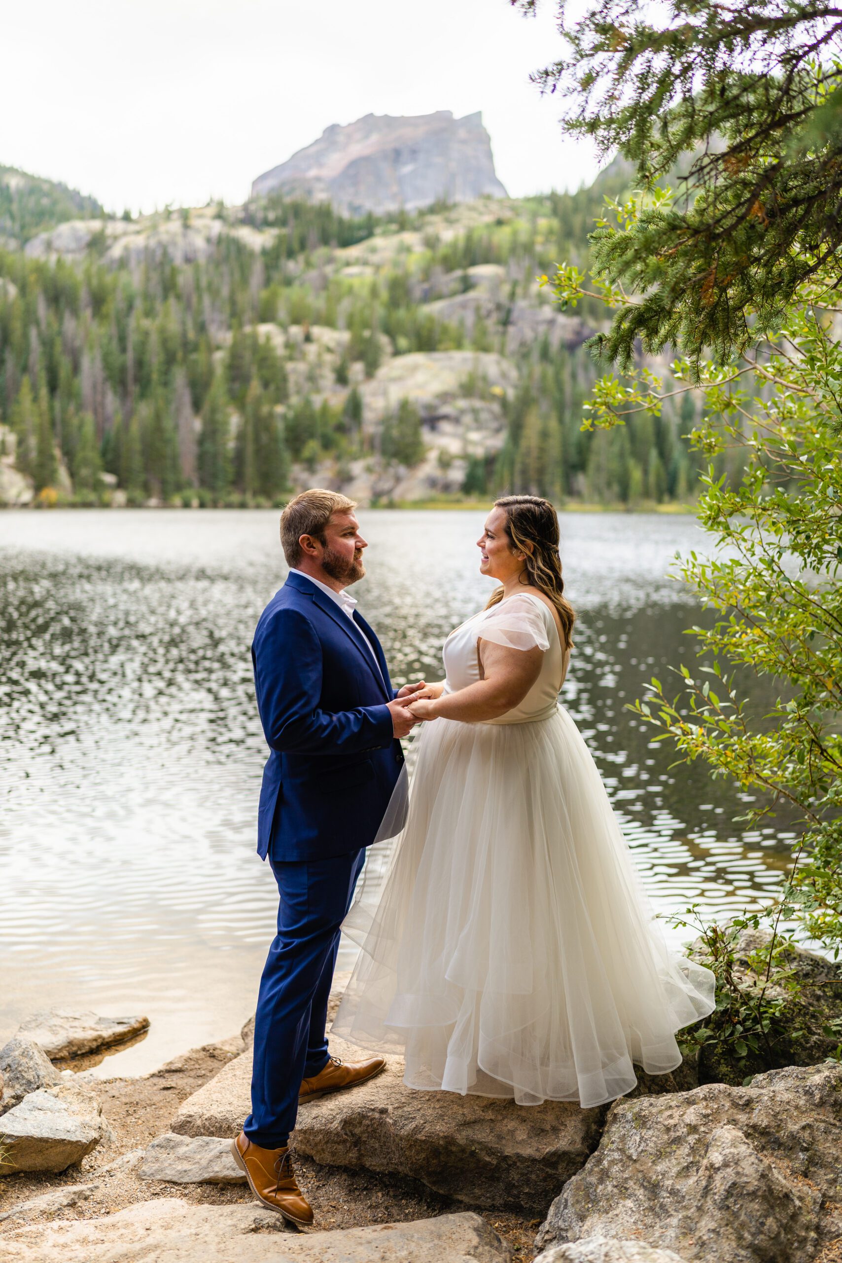 the bride and groom holding hands and looking at each other, the beautiful lake in the distance at their Bear Lake elopement. 