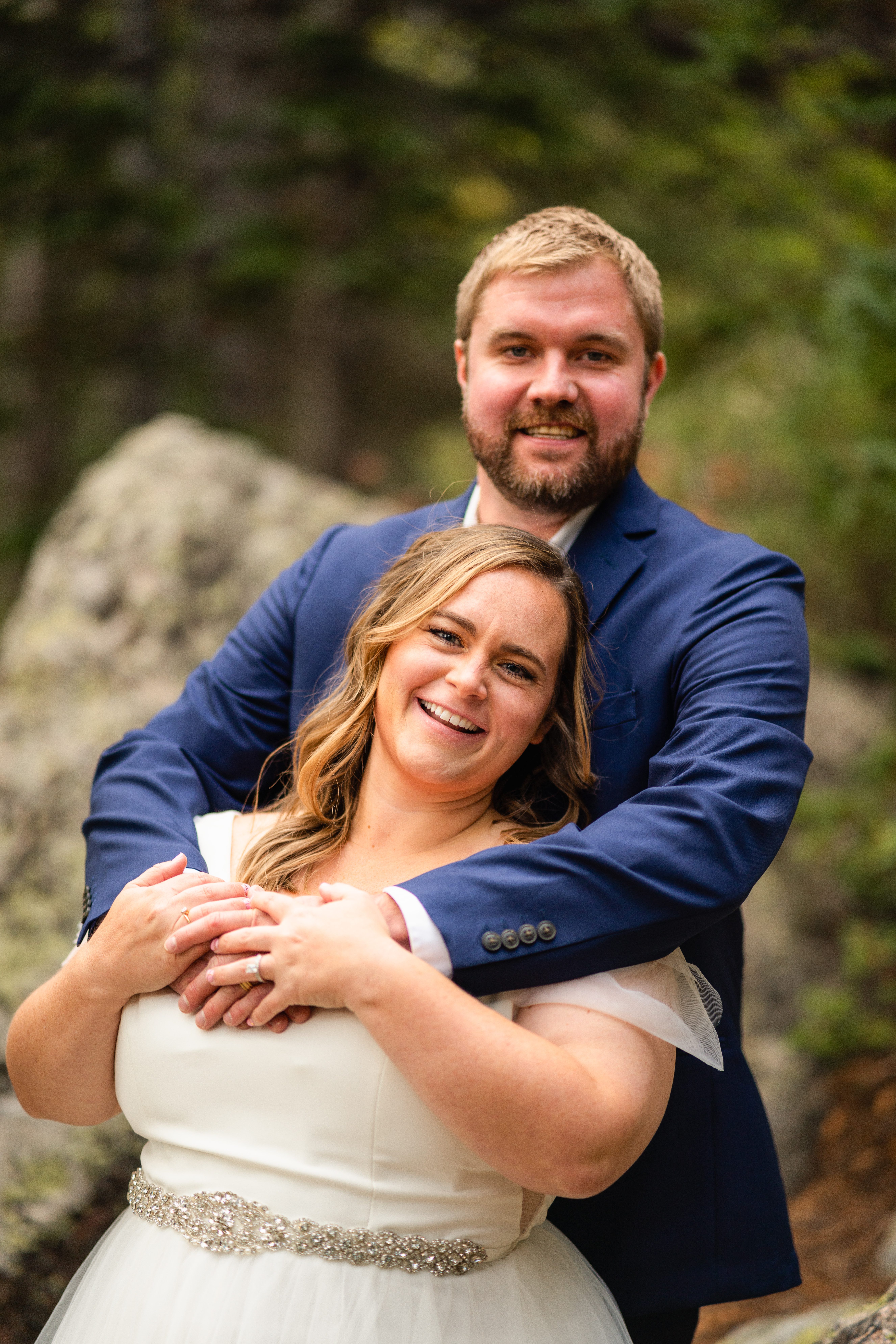 the bride in her grooms arms, both are smiling at the camera at their Bear Lake elopement. 
