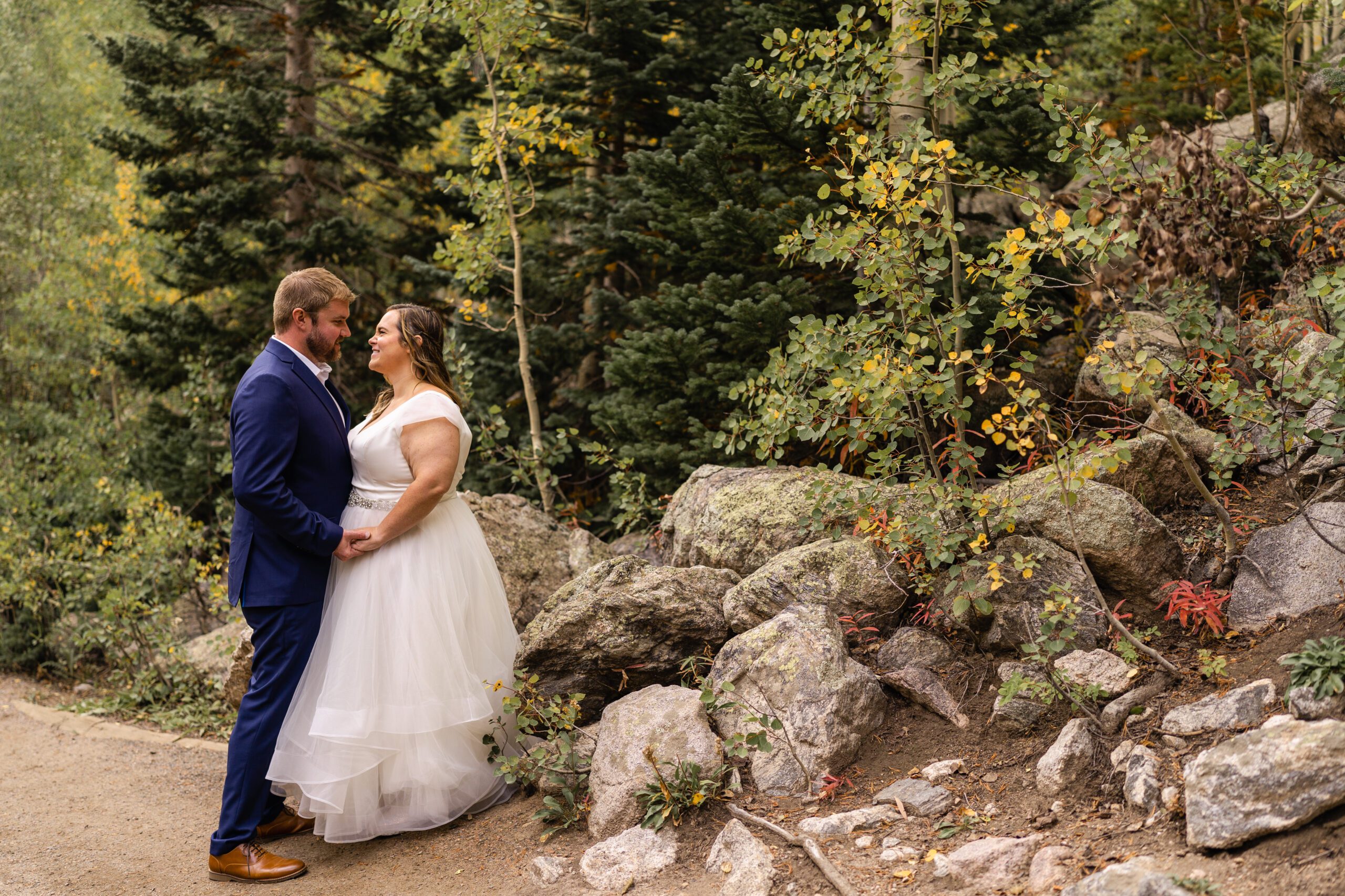 the bride and groom standing together, holding hands,  looking at each other, at their Bear Lake elopement. 