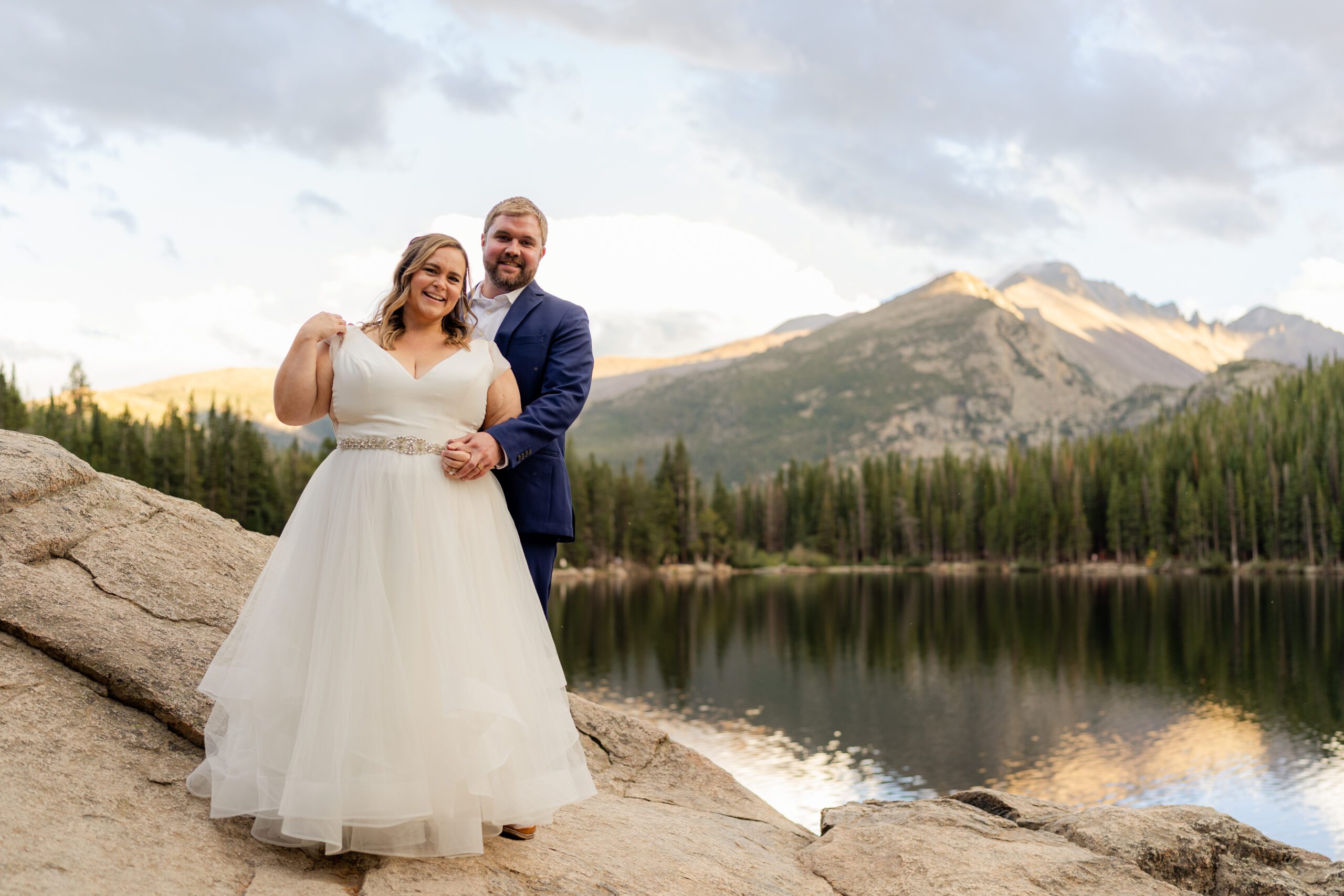the bride and groom near the lake, stand on a large boulder at their Bear Lake elopement. 