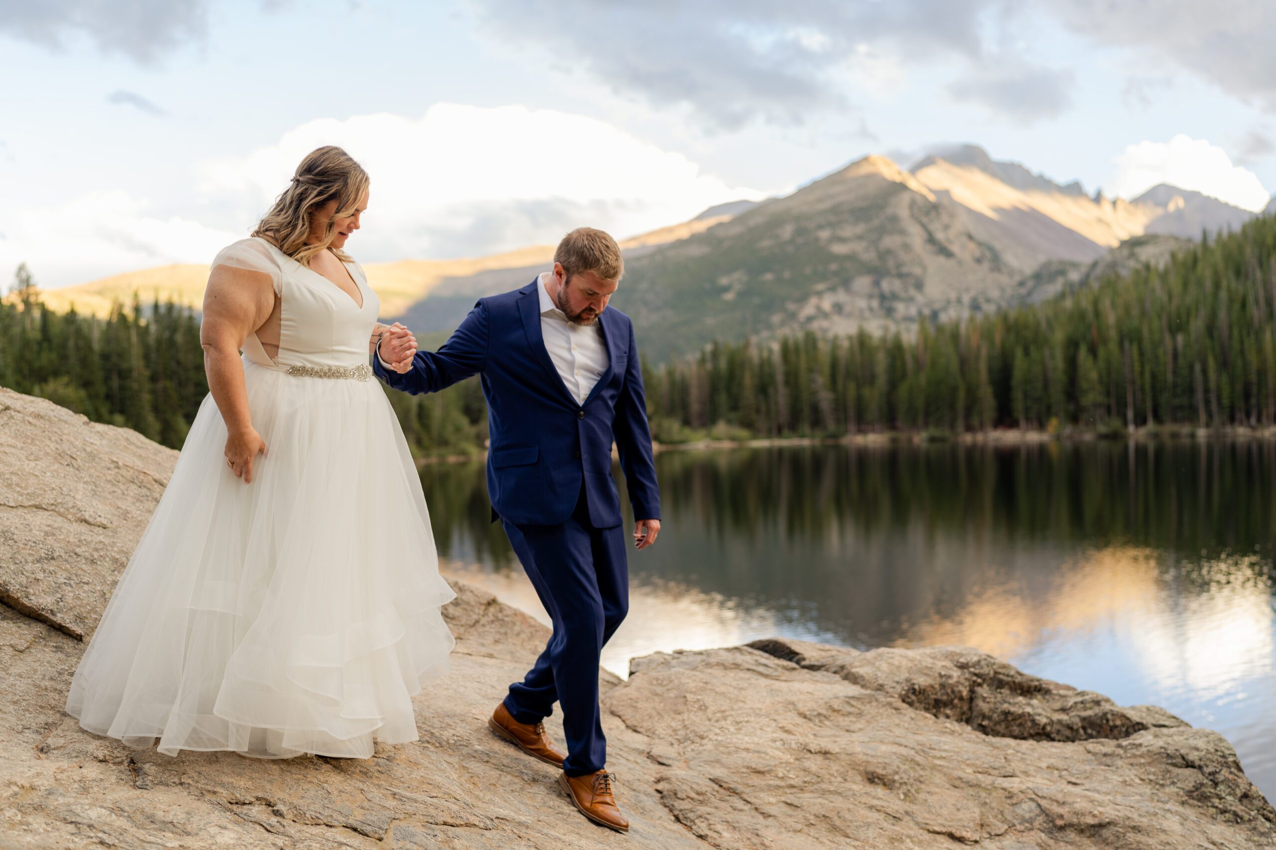 groom guides his bride down the boulder at their their Bear Lake elopement. 