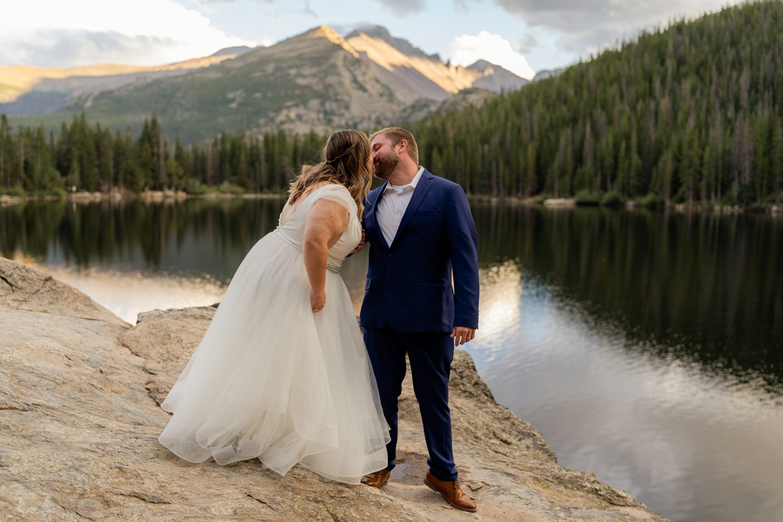 bride and groom kissing - the gorgeous lake behind them with a mountain in the distance at their Bear Lake elopement. 