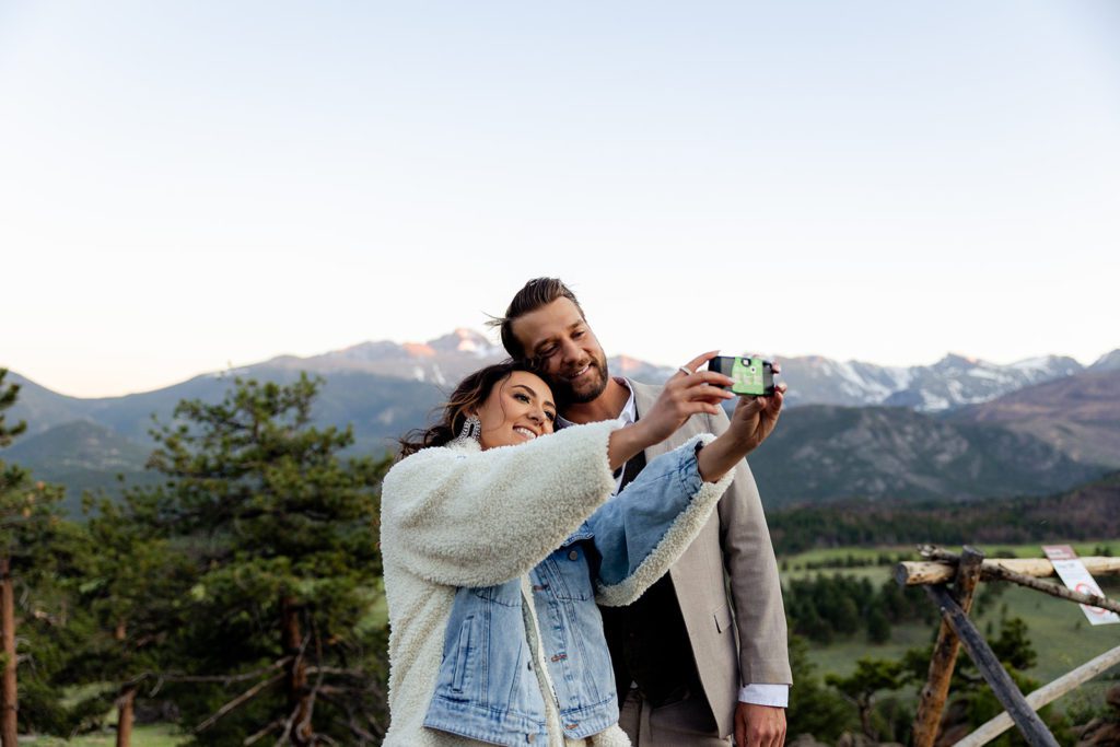 the bride holds out a disposable camera and takes a photo of the groom and her. their first selfie as husband and wife. 