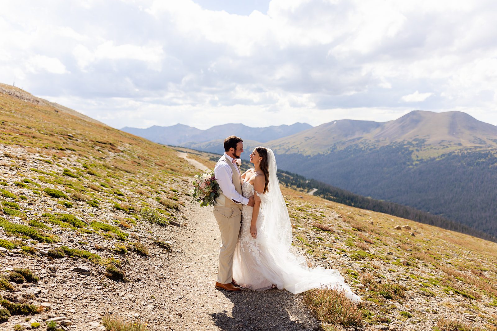 The bride and groom look lovingly at each other on the trail. 