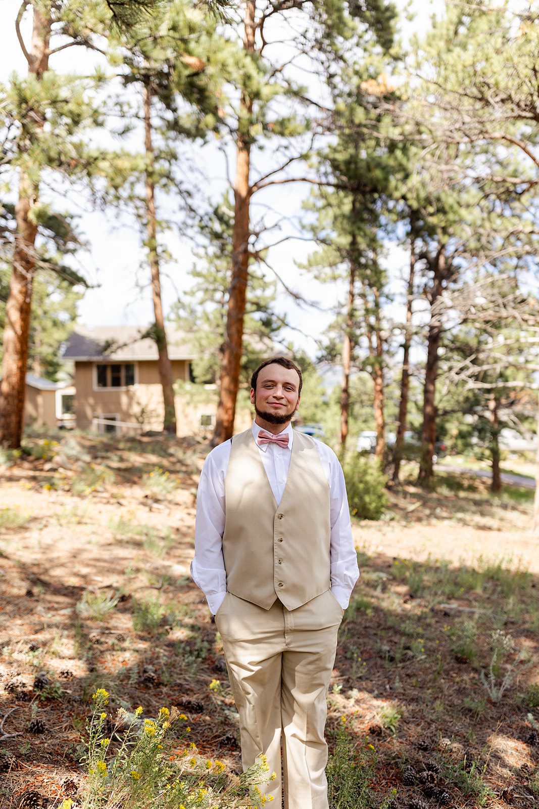 The groom, wearing a tan suit waits patiently for a first look with his bride. 