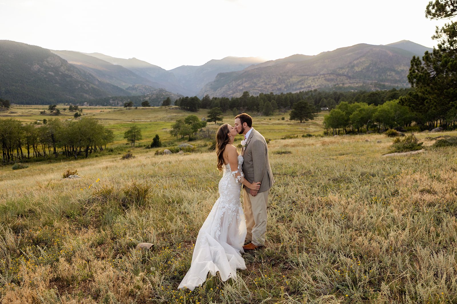 The bride and groom kiss at sunset in the valley. 
