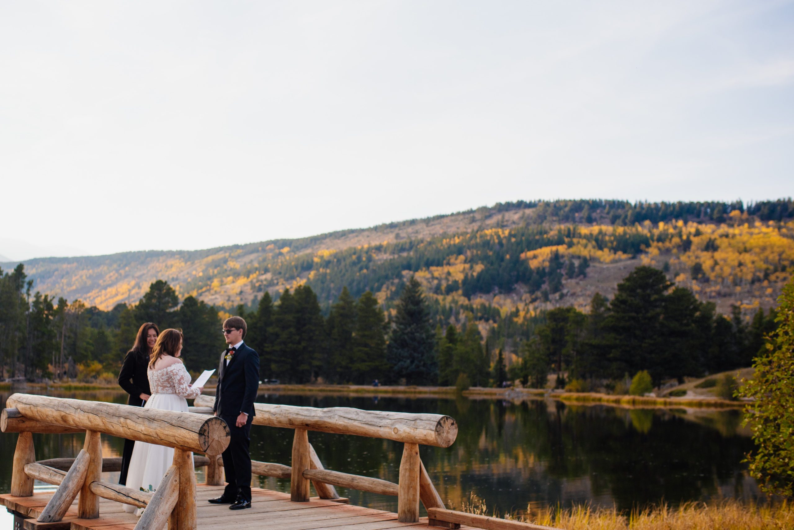 Bride reads vows to groom, a beautiful lake is behind them at Sprague Lake - RMNP