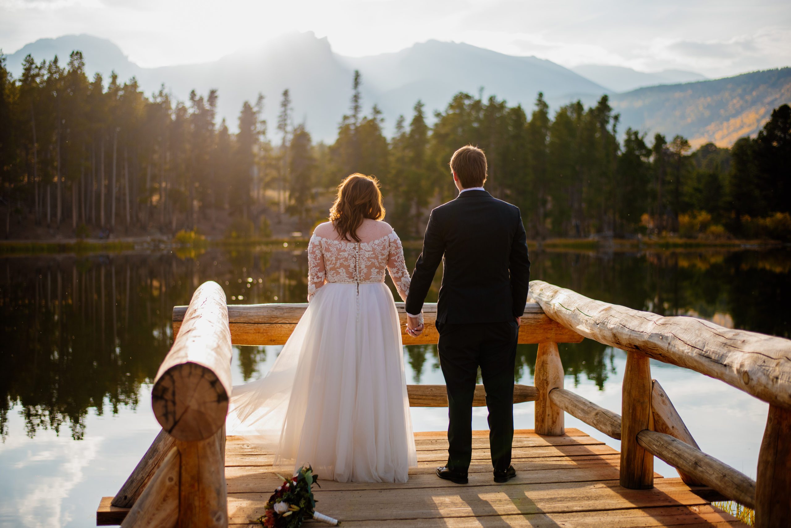Bride and groom holding hands looking at the lake at Sprague Lake - RMNP