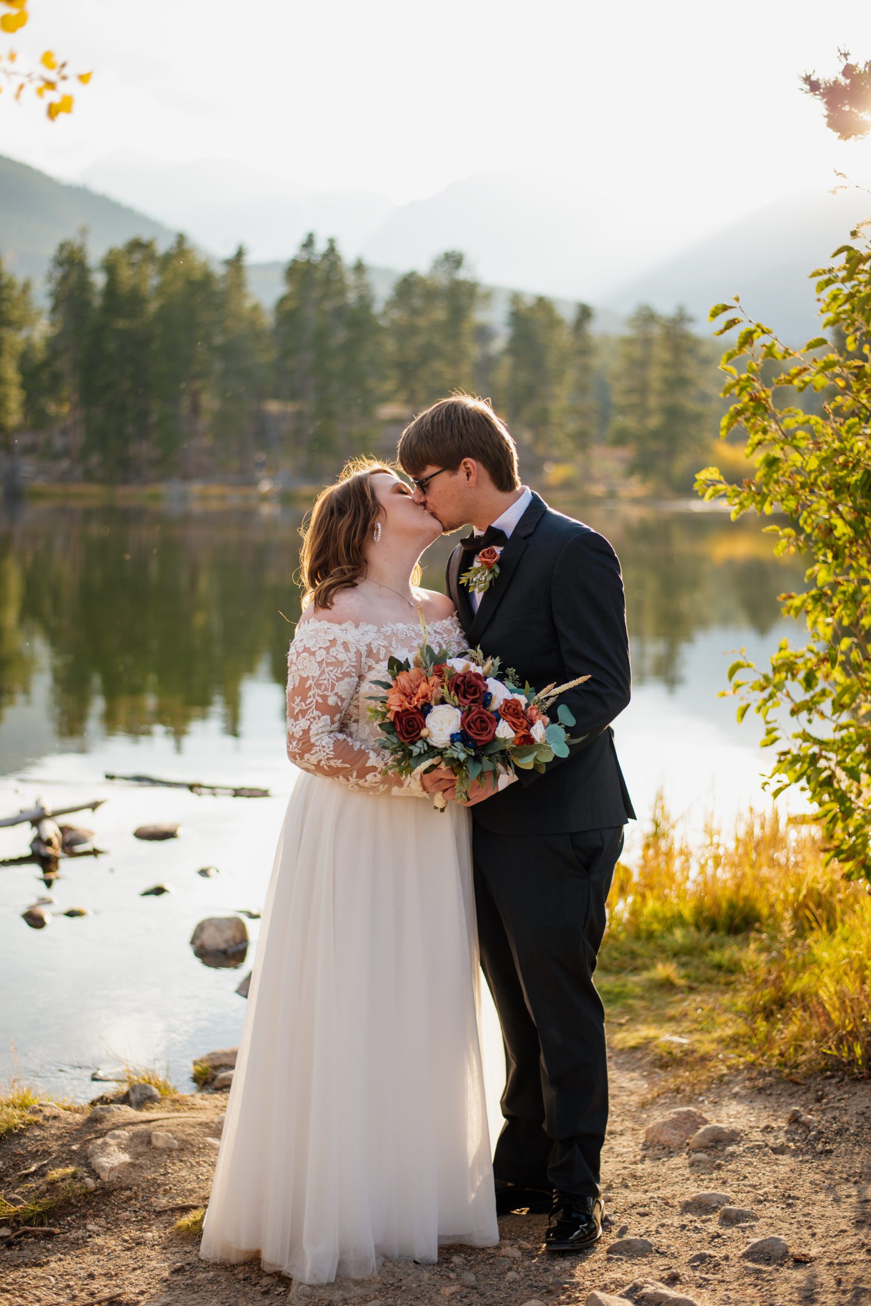 Bride and groom kiss on the lake at Sprague Lake - RMNP