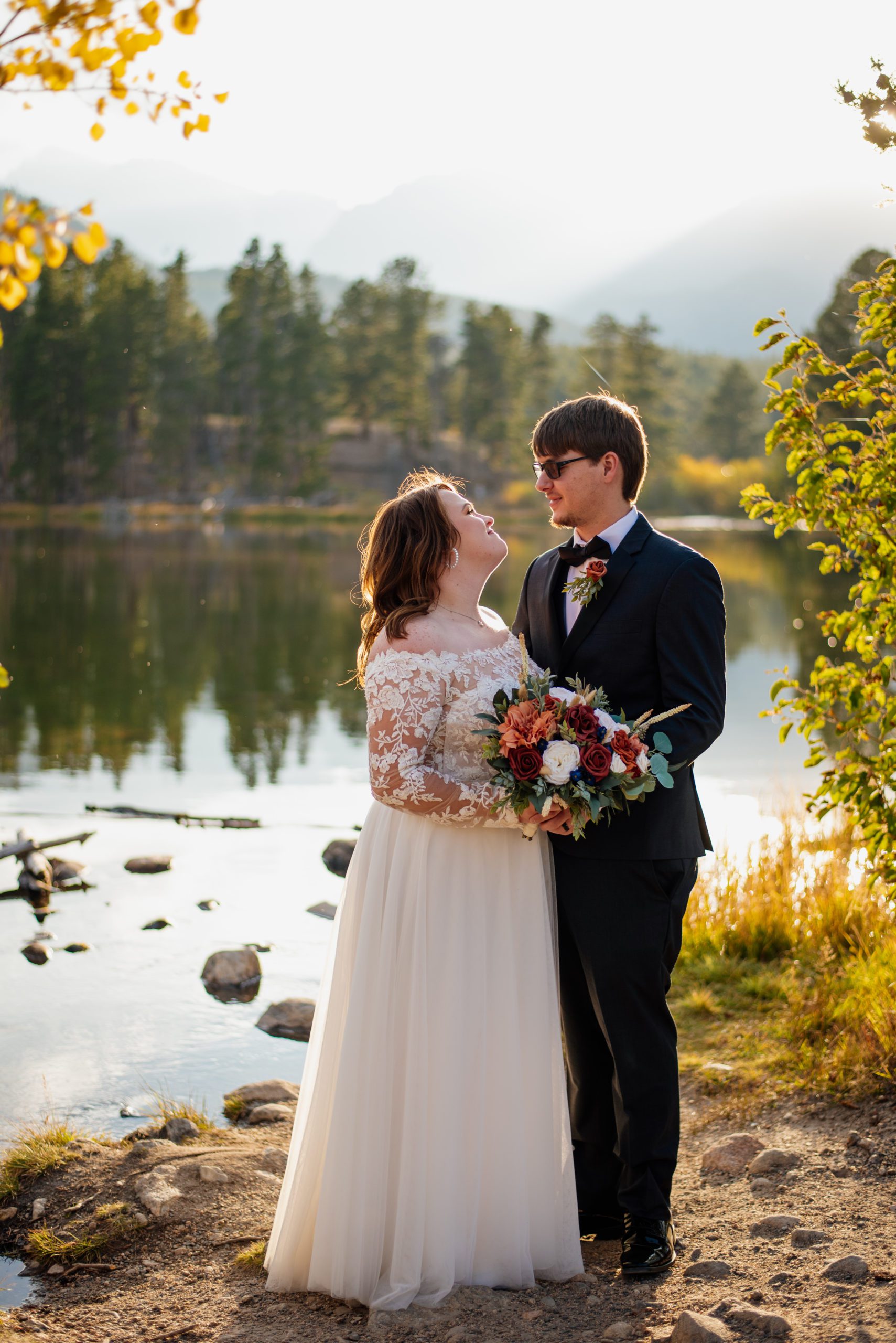 Bride and groom look at each other with happy smiles at Sprague Lake - RMNP