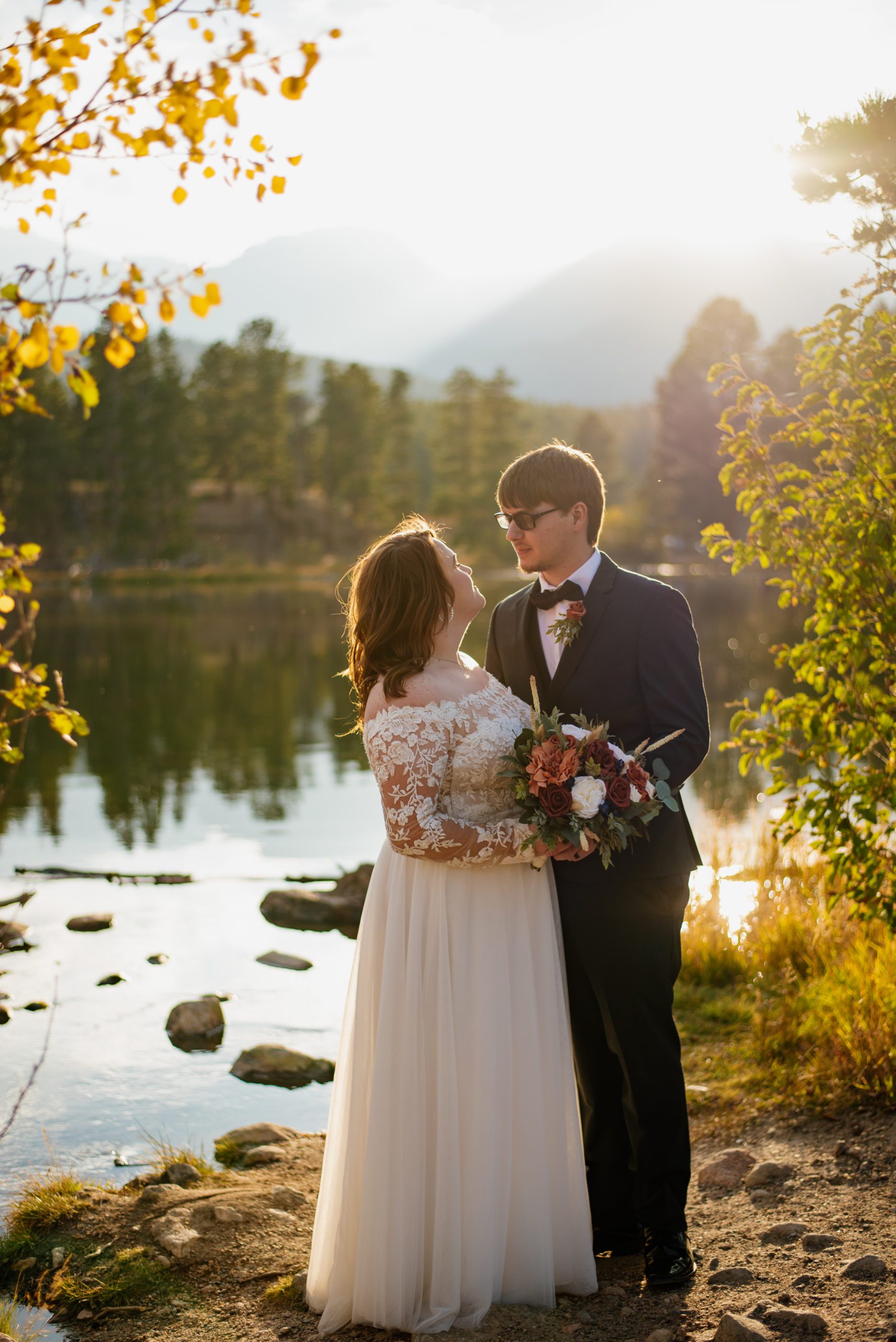 Bride and groom look at each other lovingly by the lake at Sprague Lake - RMNP