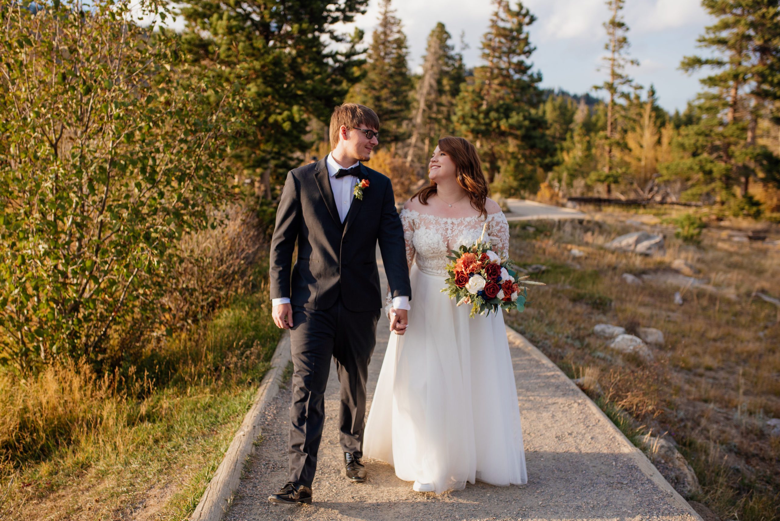 Bride and groom look at each other happily while walking around the lake at Sprague Lake - RMNP