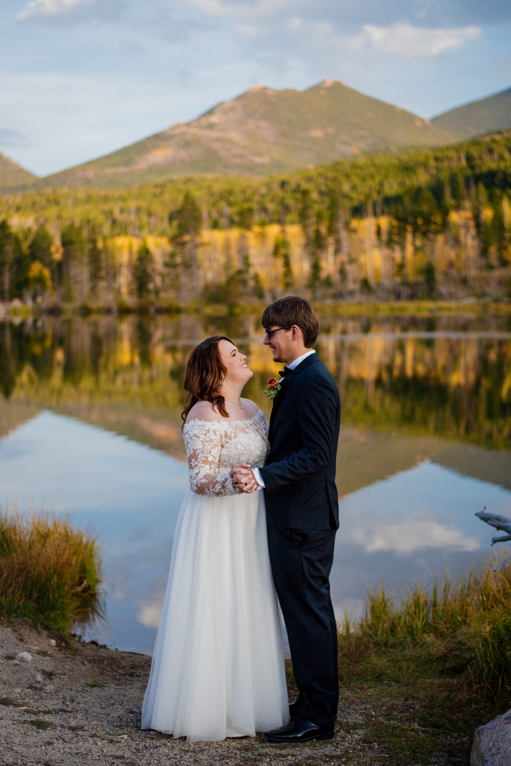 Bride and groom smile affectionately at each other at Sprague Lake - RMNP