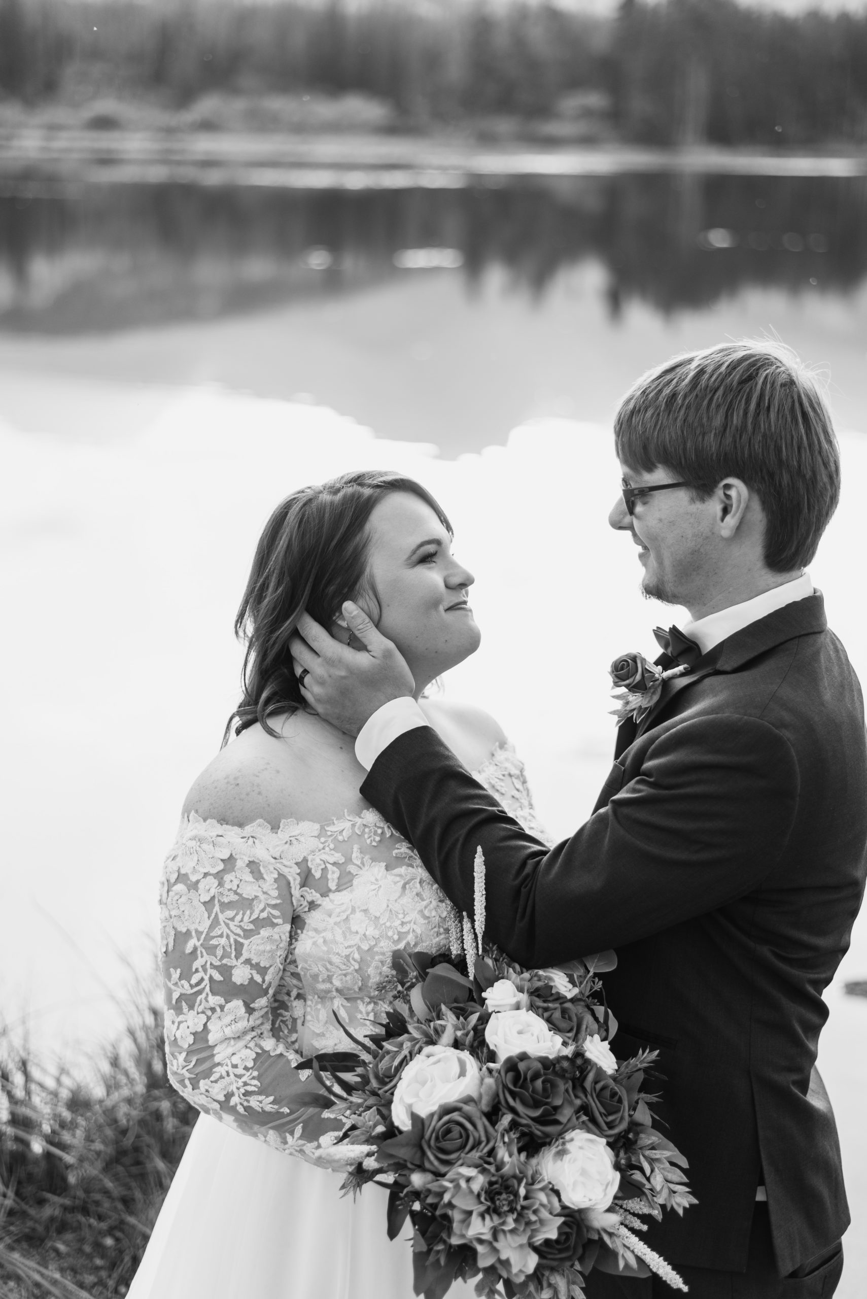 black and white photo of bride and groom - groom tucks his wife's hair behind her ear at Sprague Lake - RMNP