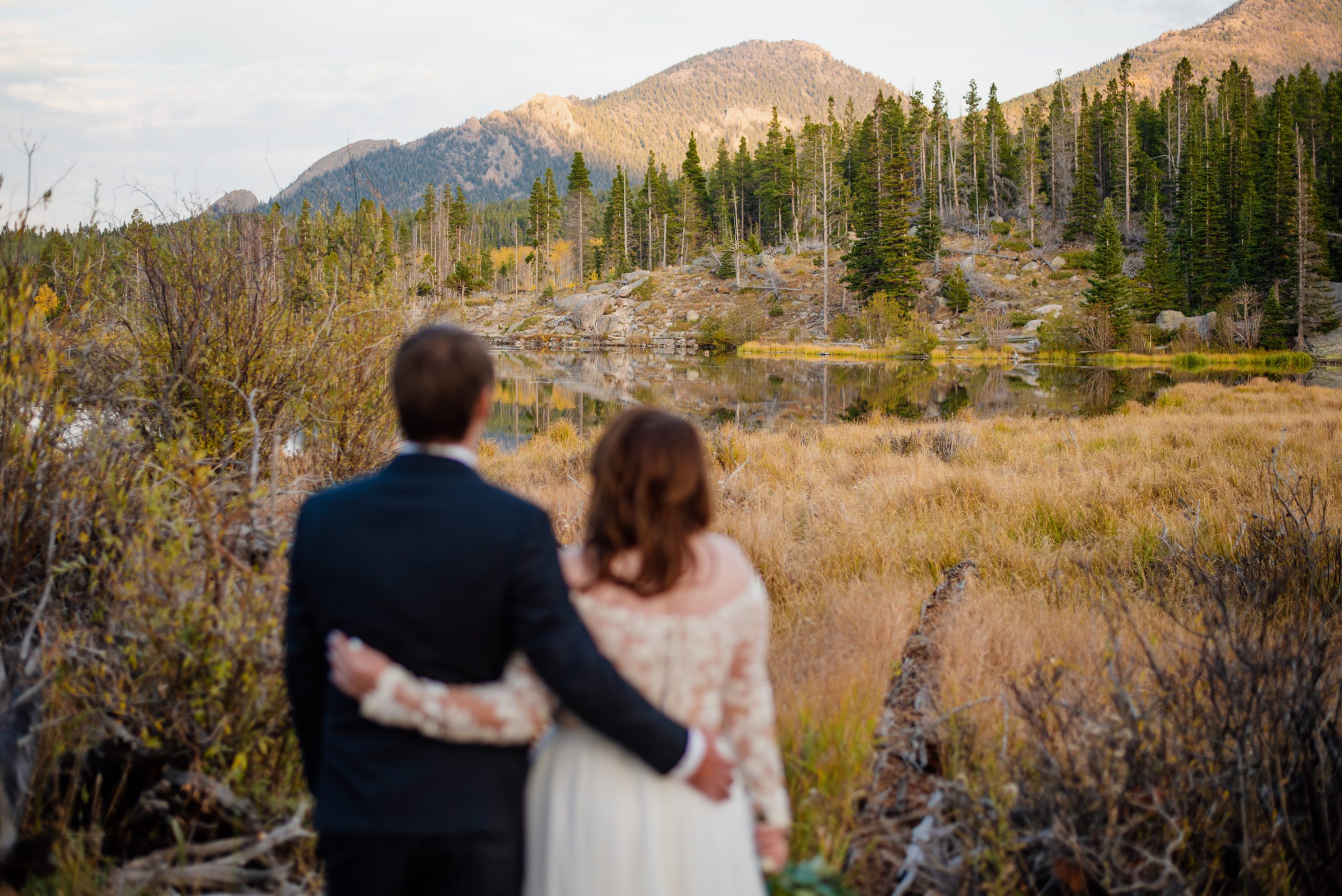 Bride and groom holding each others sides appreciation the beautiful landscape at Sprague Lake - RMNP