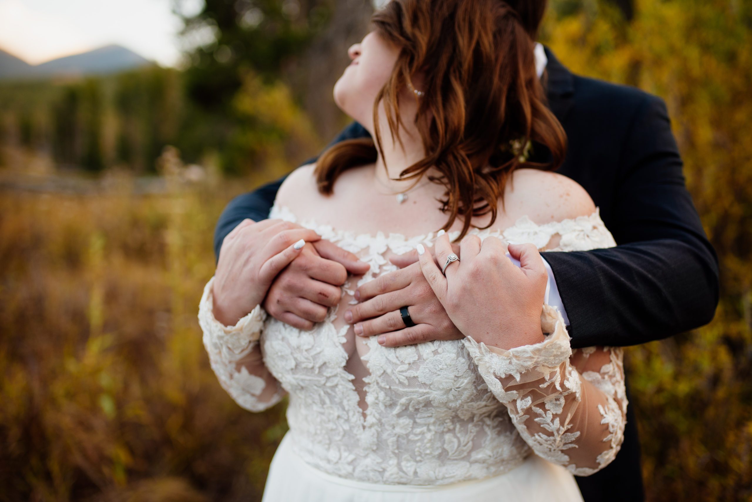 Close up shot of bride's dress with groom's hands around her chest at Sprague Lake - RMNP