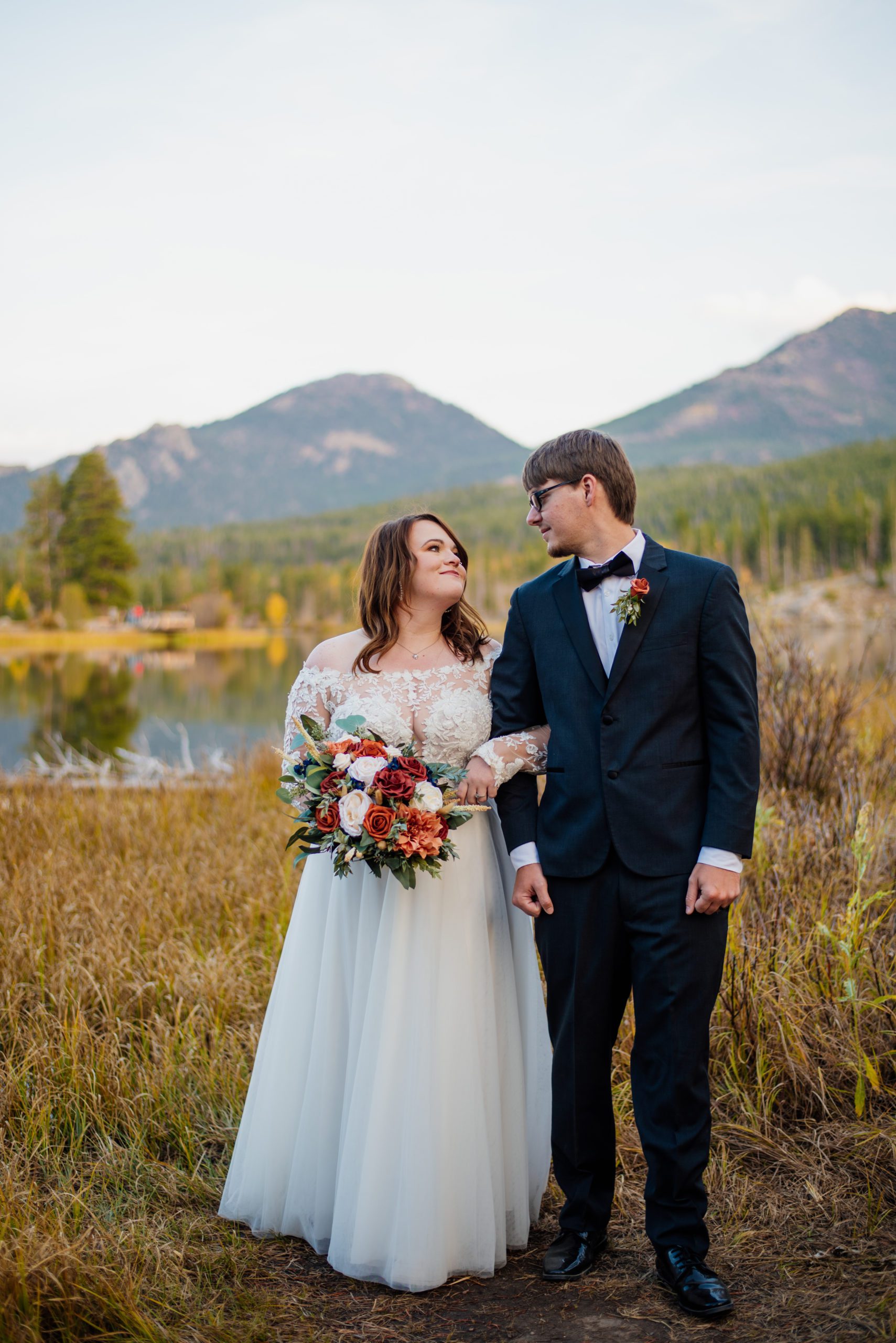 Bride and groom linked arms looking at each other at Sprague Lake - RMNP
