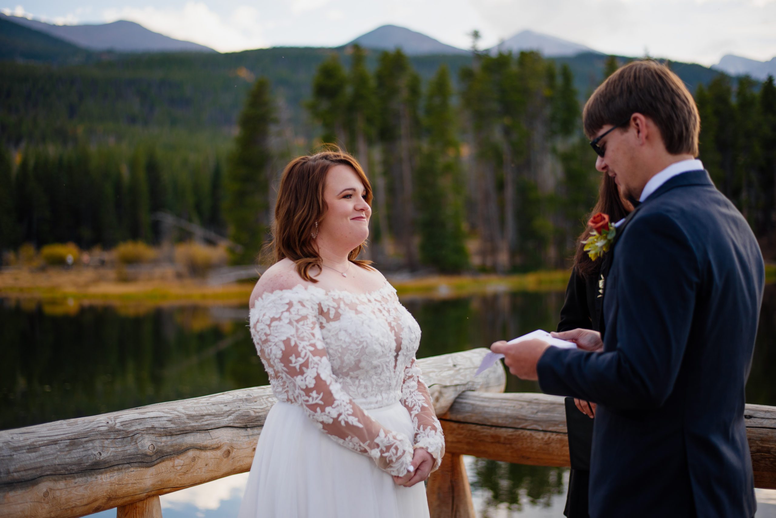 Bride smiles at groom reading vows at Sprague Lake - RMNP