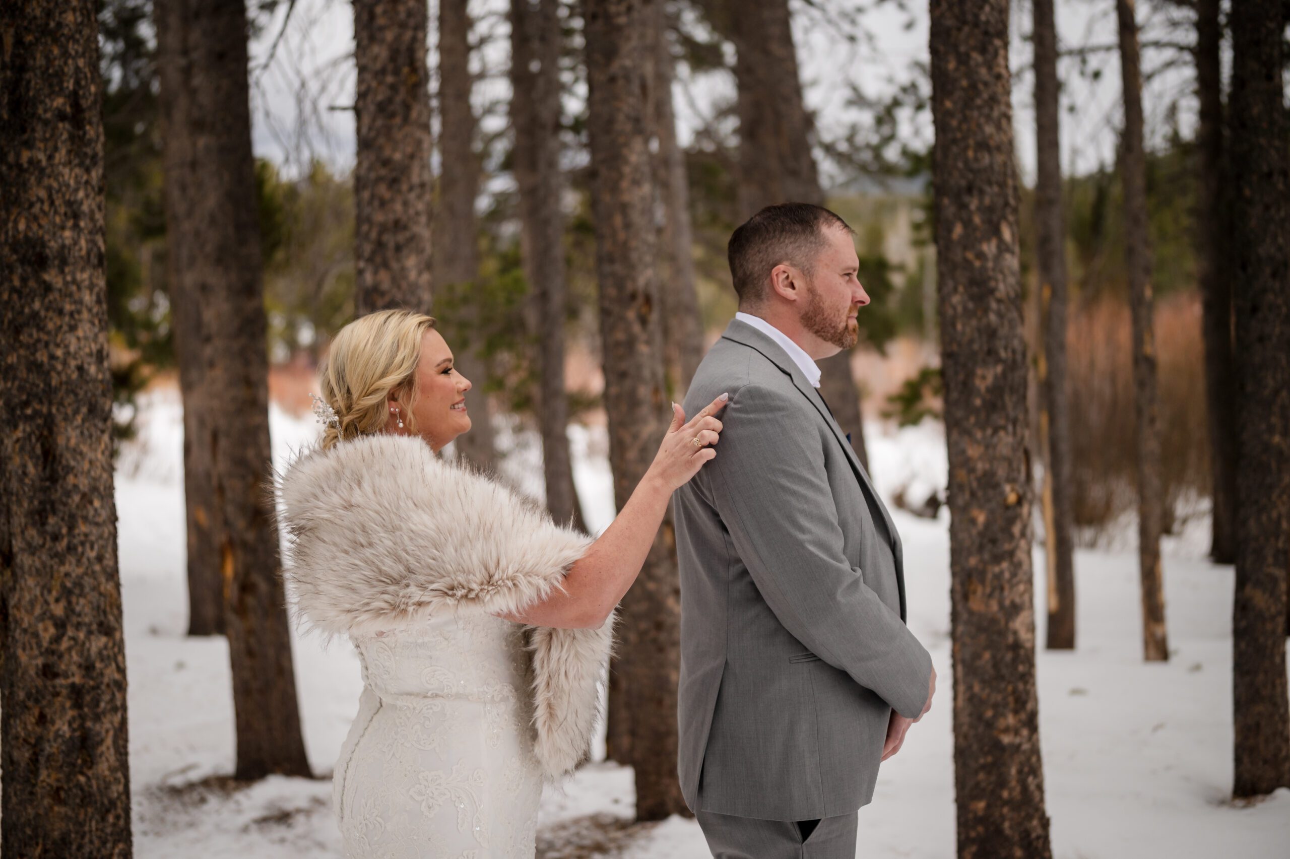 Bride taps her groom on the shoulder during their first look at their Winter Elopement at Sprague Lake.