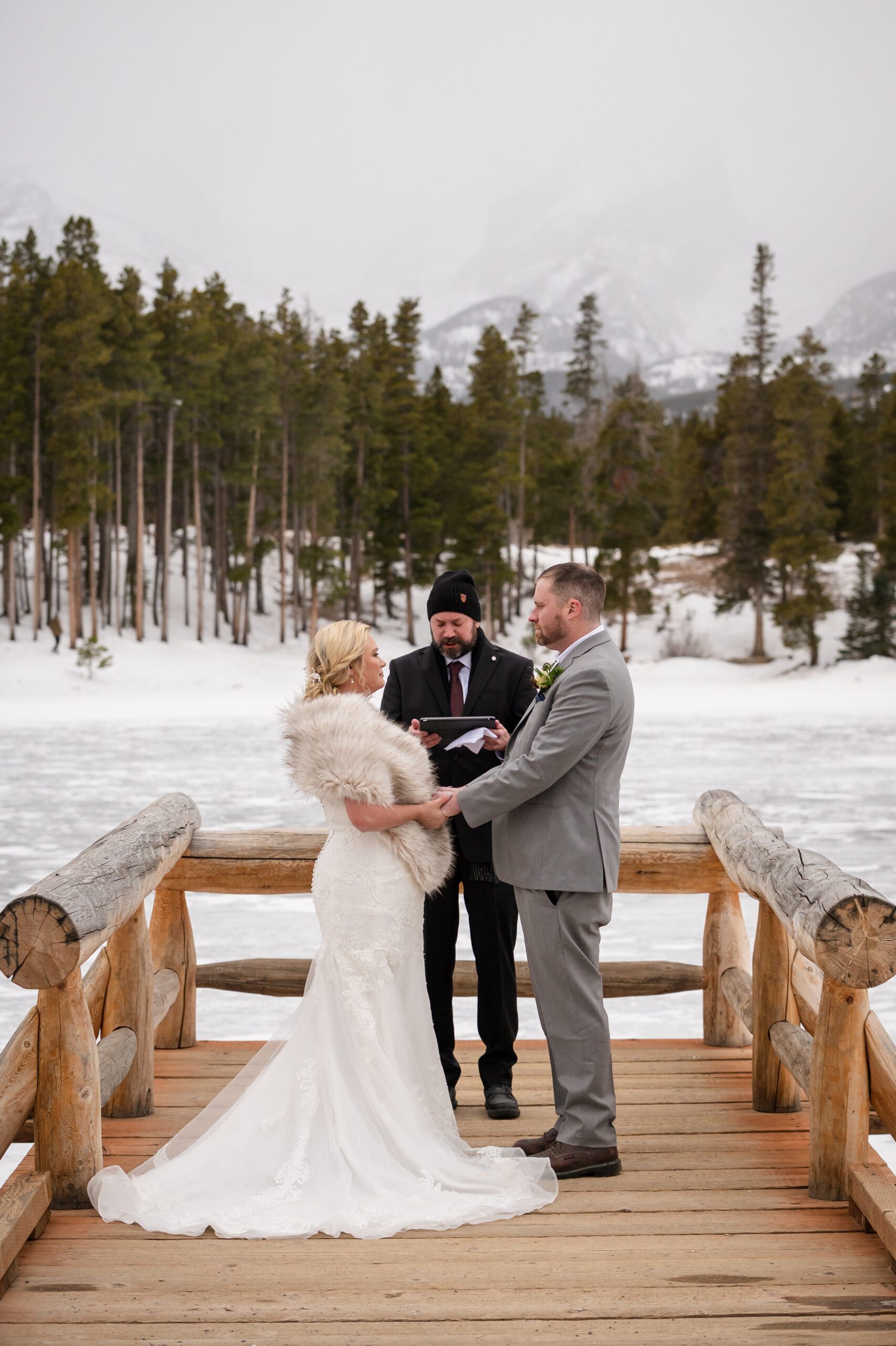 The bride and groom hold hands during their Winter Elopement ceremony at Sprague Lake. 