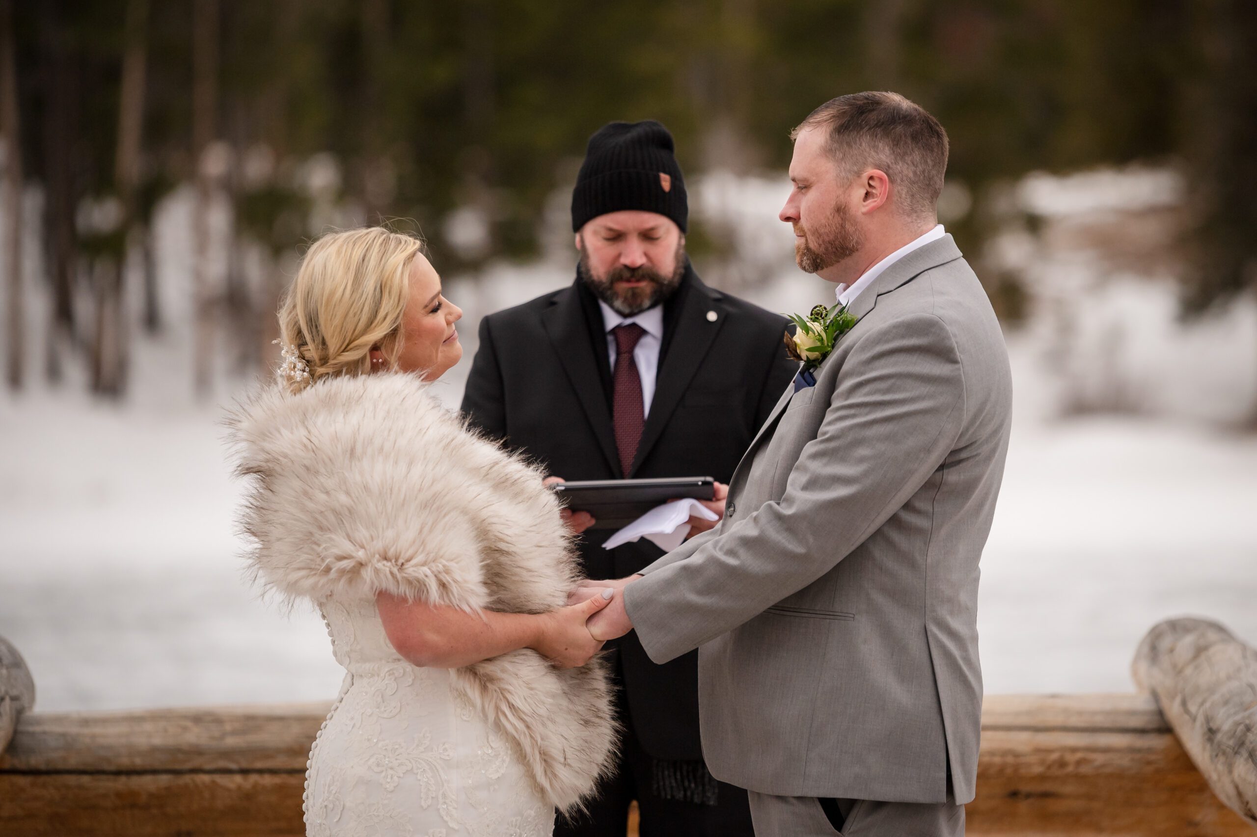 the bride and groom holding hands during their ceremony at their Winter Elopement at Sprague Lake.