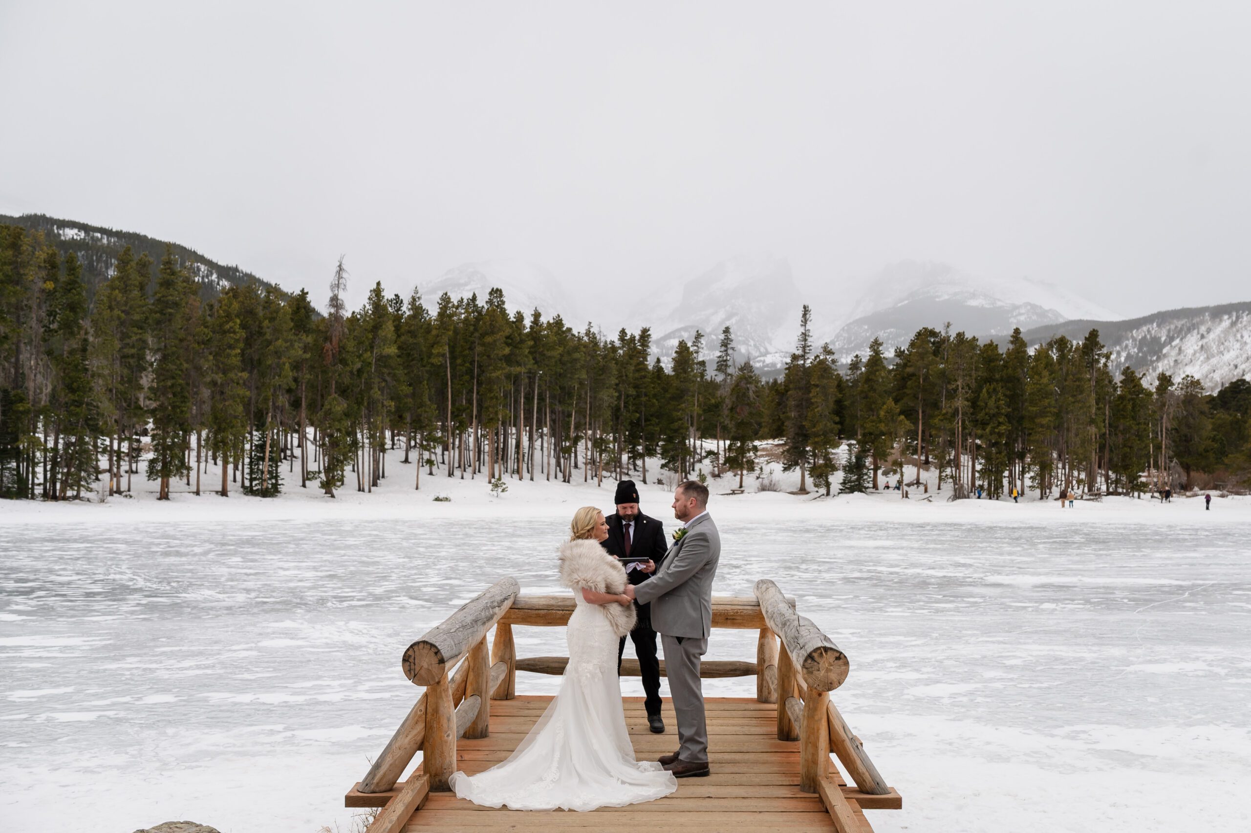 the gorgeous Colorado mountains in the distance as the bride and groom have their ceremony at their Winter Elopement at Sprague Lake. 