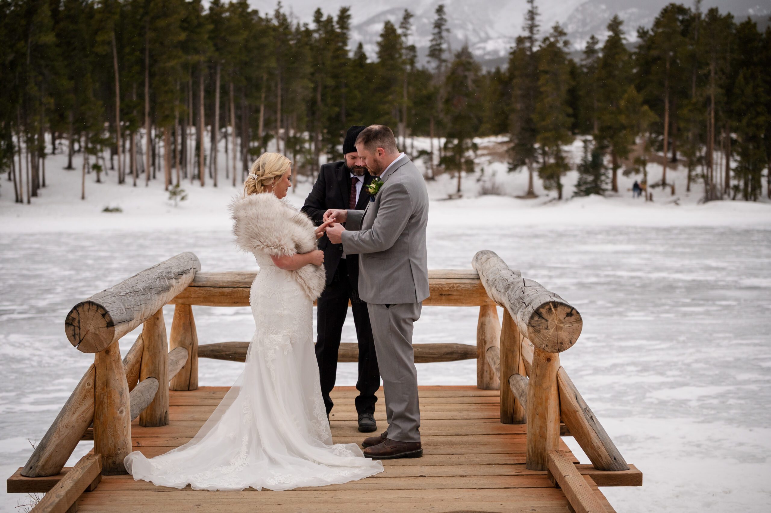 groom places ring on his bride's finger during their Winter Elopement at Sprague Lake. 