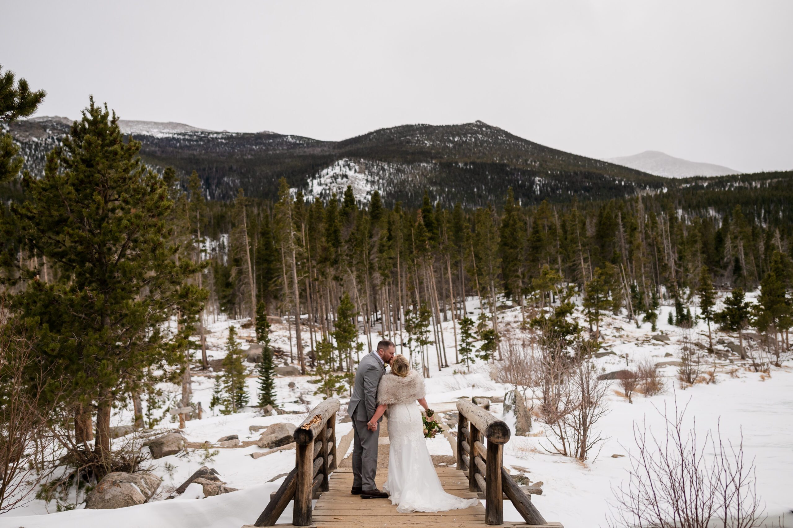 bride and groom kissing on a bridge at their Winter Elopement at Sprague Lake. 