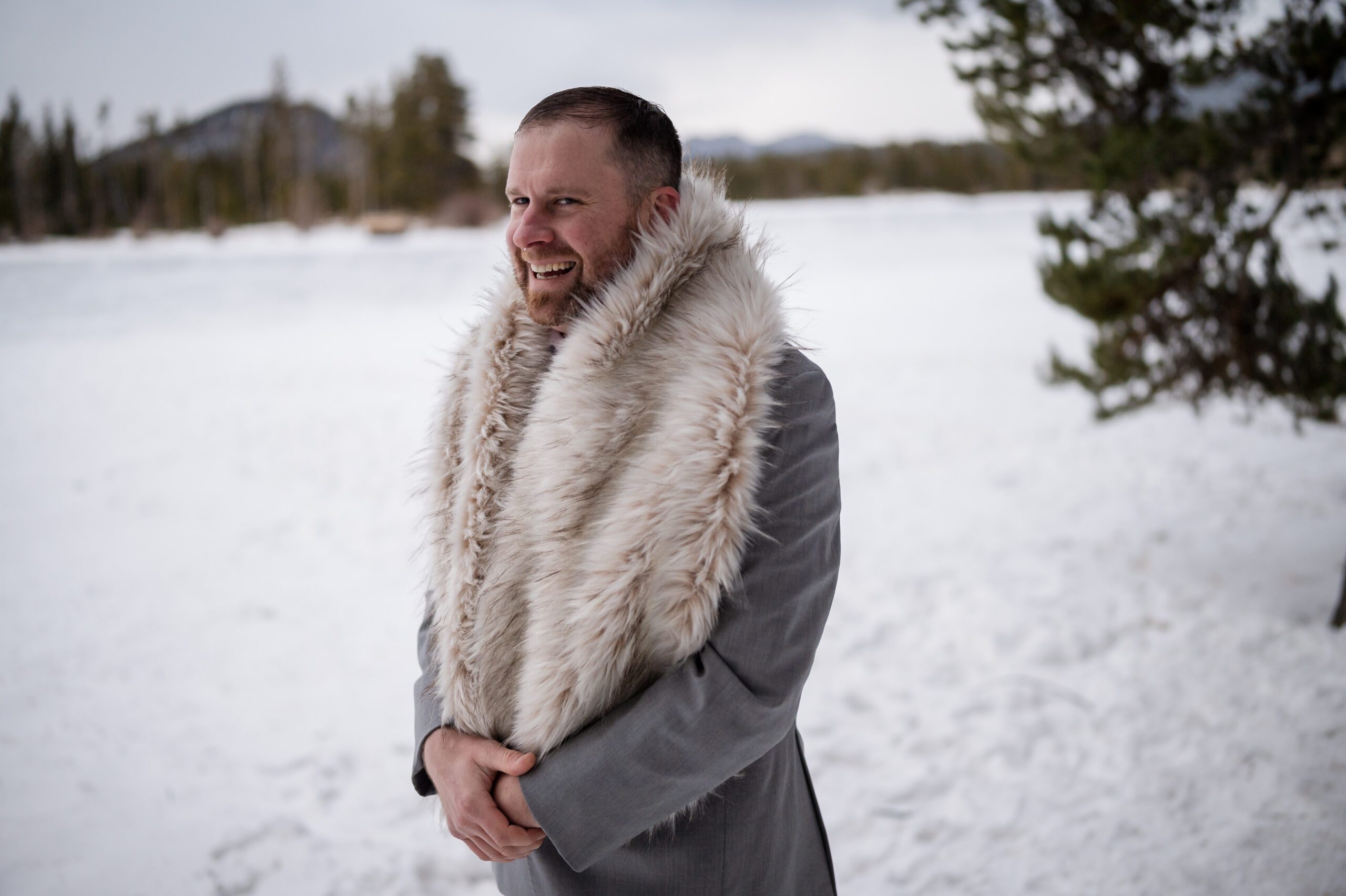 the groom wearing his bride's shawl during their Winter Elopement at Sprague Lake. 