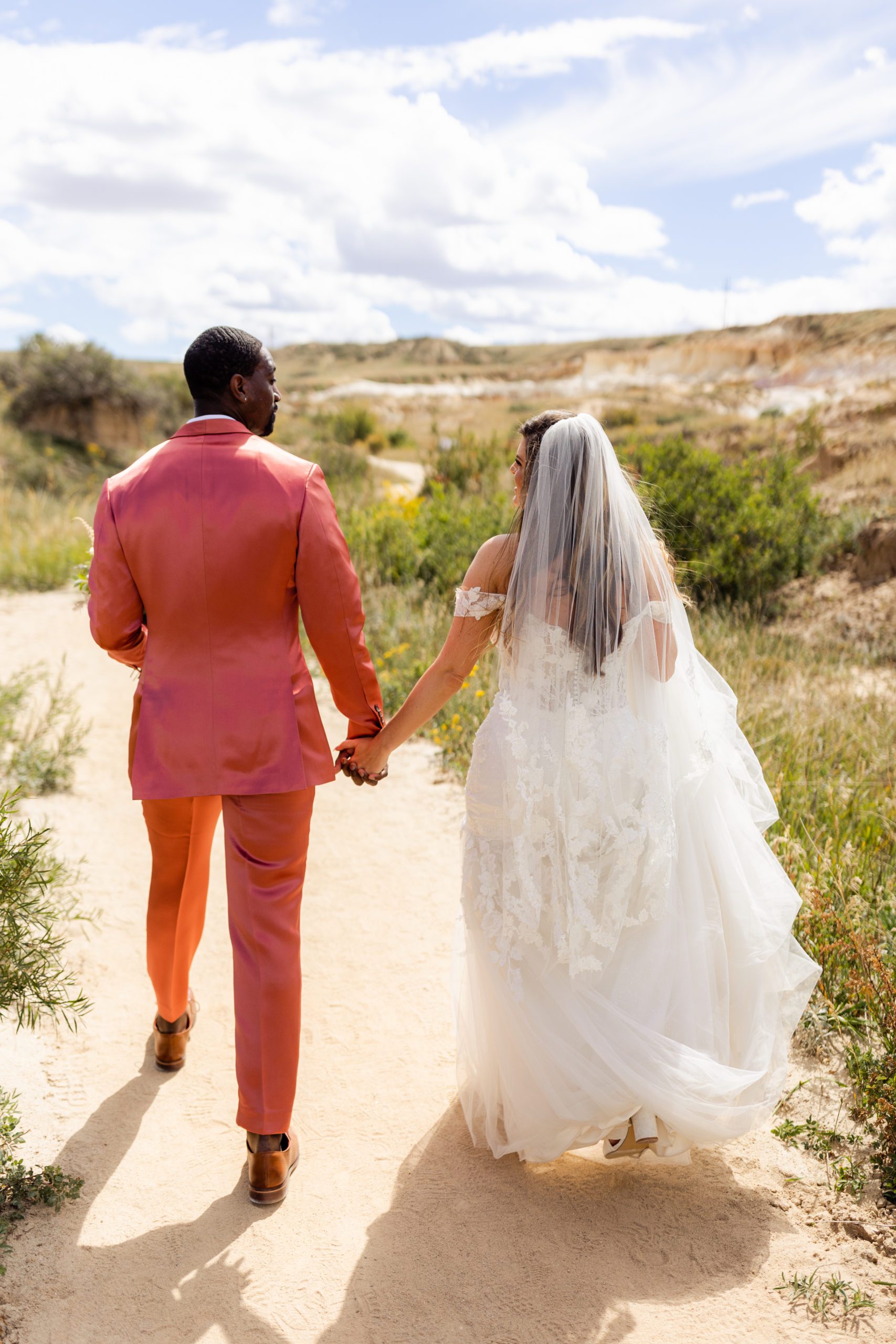 Groom and his bride walking hand in hand at the Paint Mines before their elopement at the Garden of the Gods