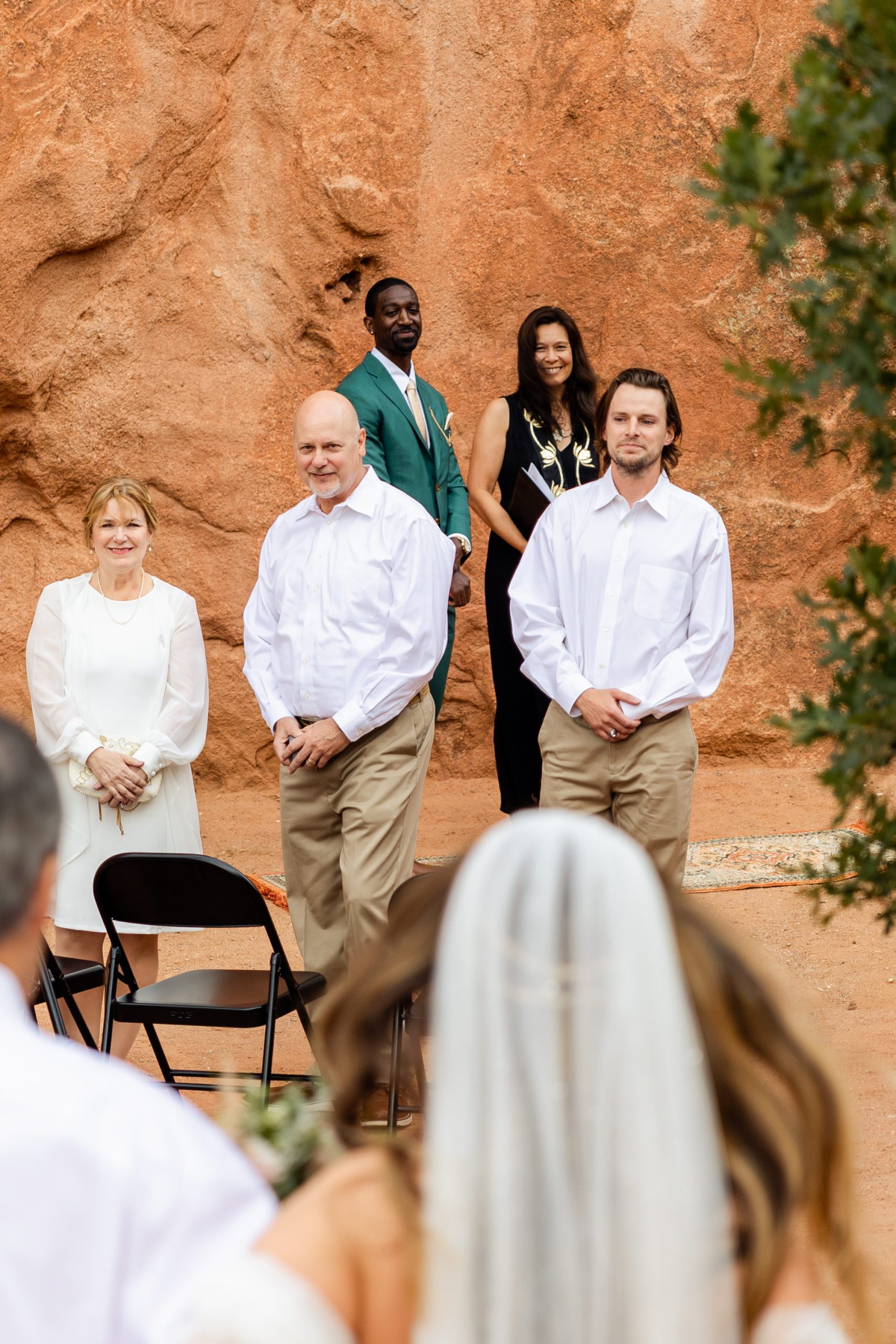 The wedding guests stand, smiling as the bride walks down the aisle for her elopement at the Garden of the Gods