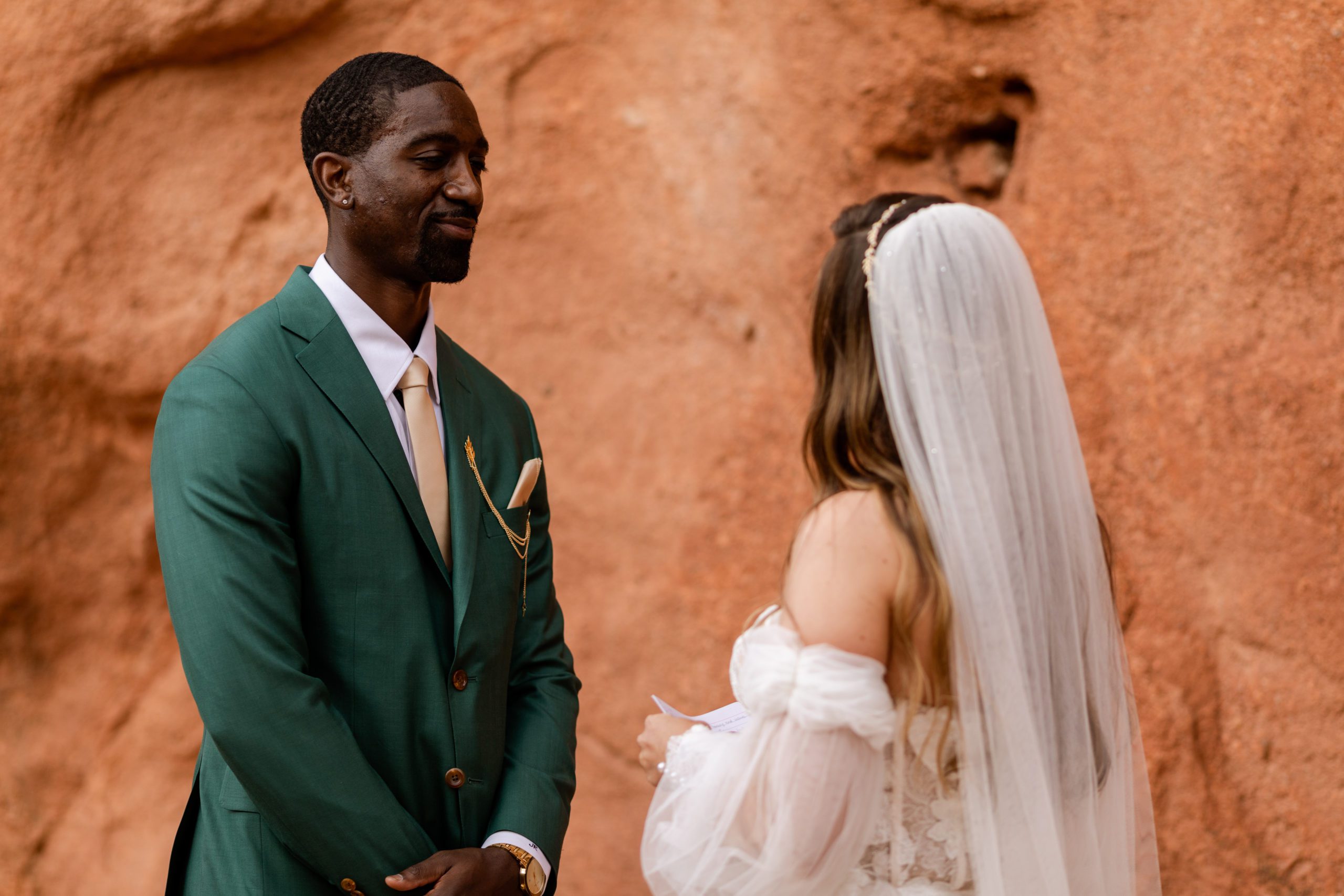 Groom smiles at the Bride as she reads her vows during their elopement at the Garden of the Gods