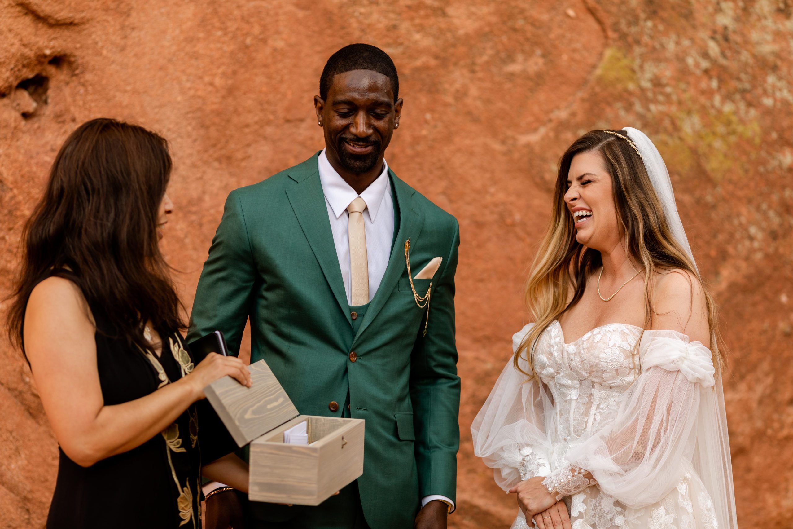 Bride laughs as officiant shows the bride and groom their wine box during their ceremony  at the Garden of the Gods