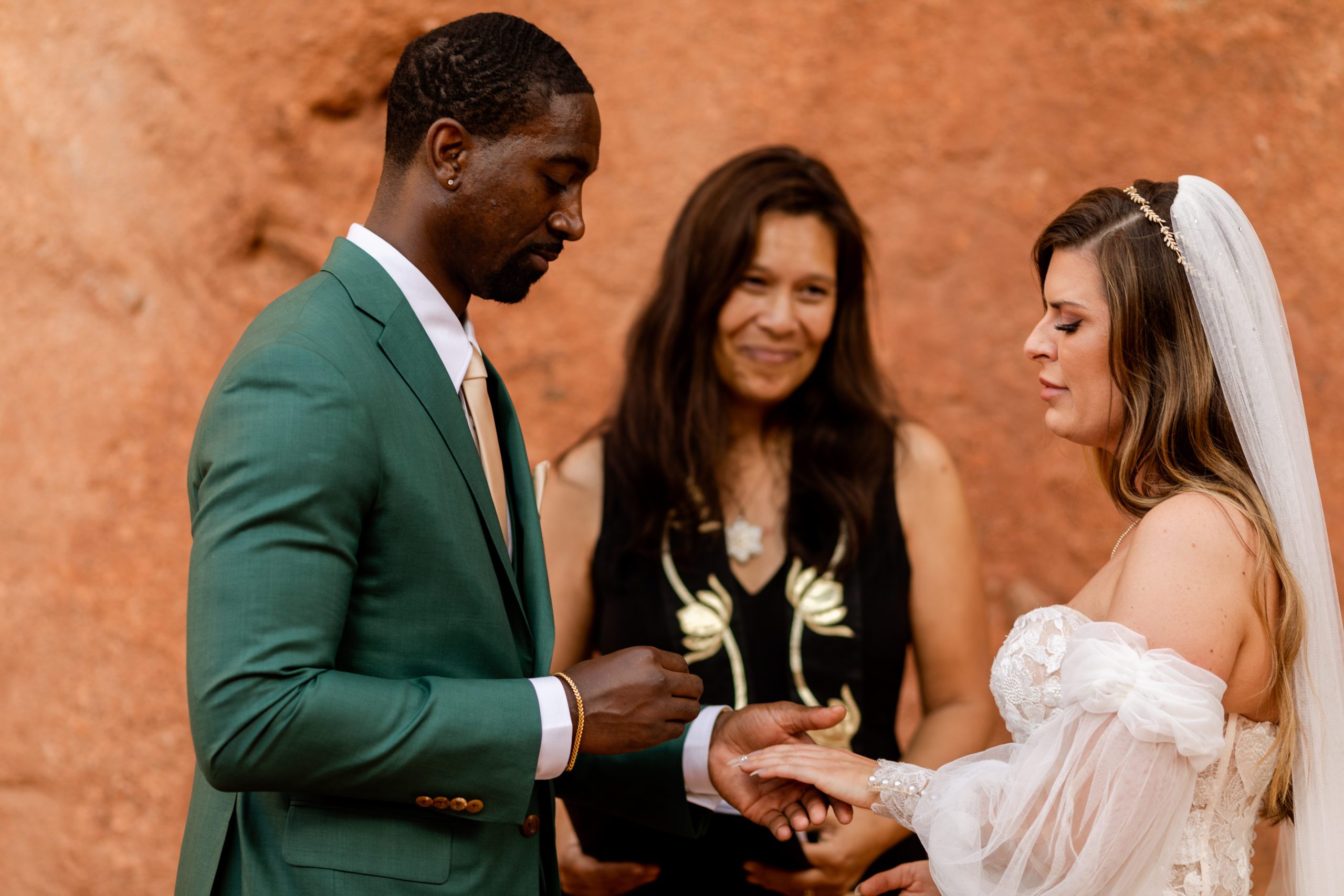 Groom places ring on his brides fingers during elopement at the Garden of the Gods