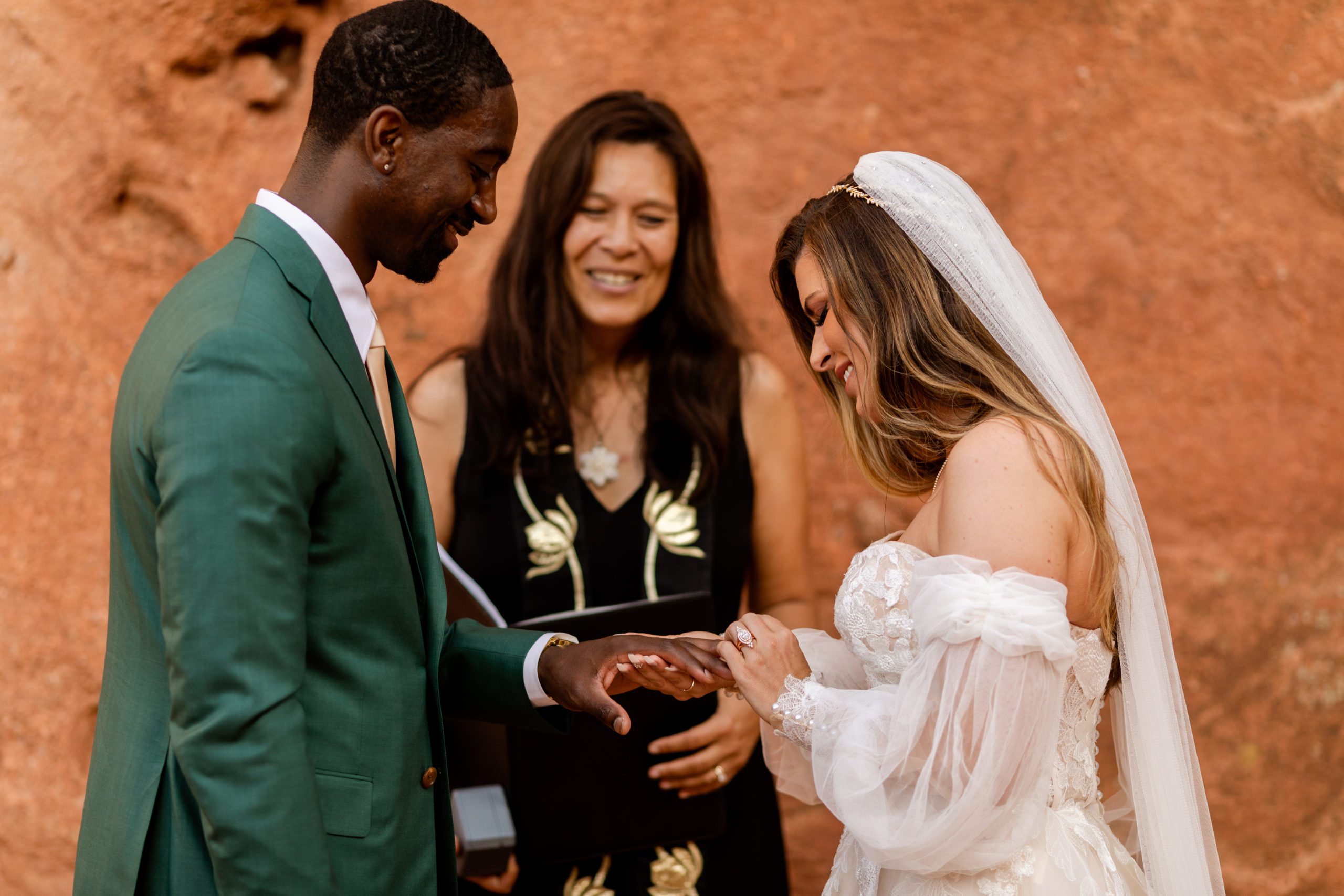 Bride places ring on her grooms fingers during elopement at the Garden of the Gods.