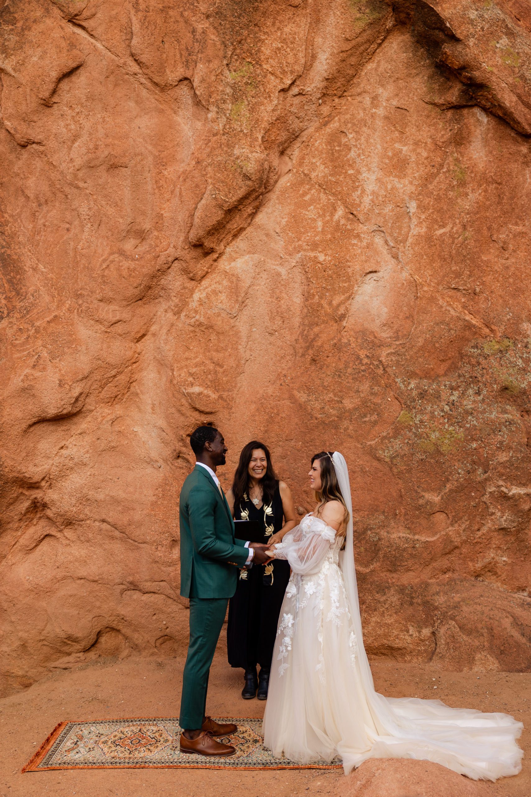 Bride and groom hold hands, smiling at each other during their ceremony at their elopement at the Garden of the Gods