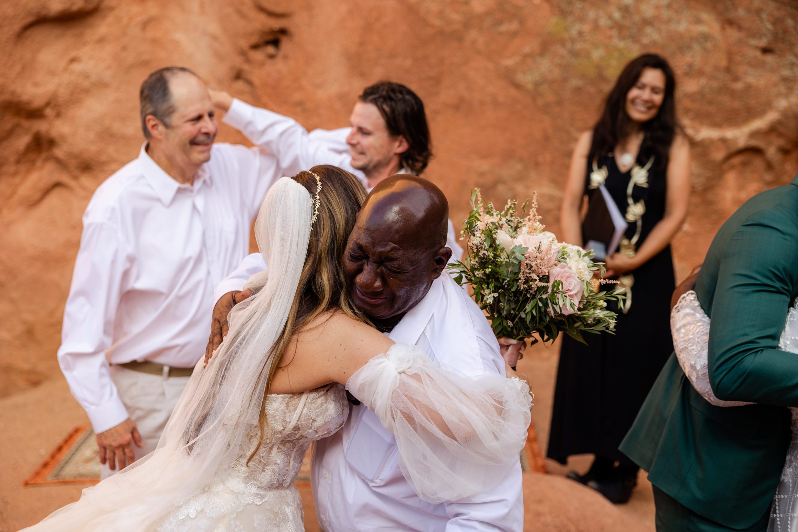 Bride hugs her emotional father in law after their ceremony at the garden of the gods. 